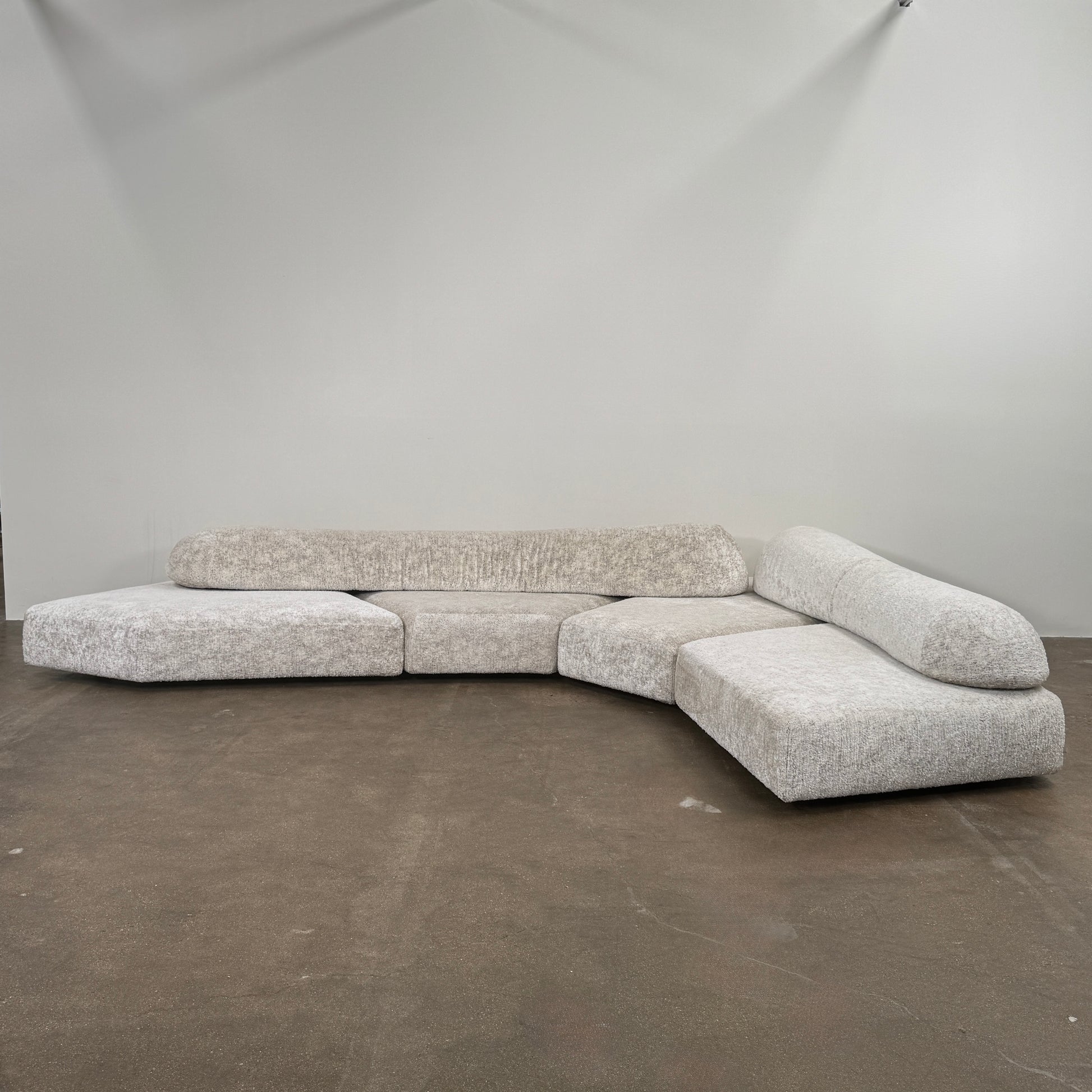 The Edra On The Rocks 4 piece Modular Sofa by Edra is a modern, light gray L-shaped sofa with customizable seating, featuring low rounded backrests and wide flat cushions, shown on a plain white background.