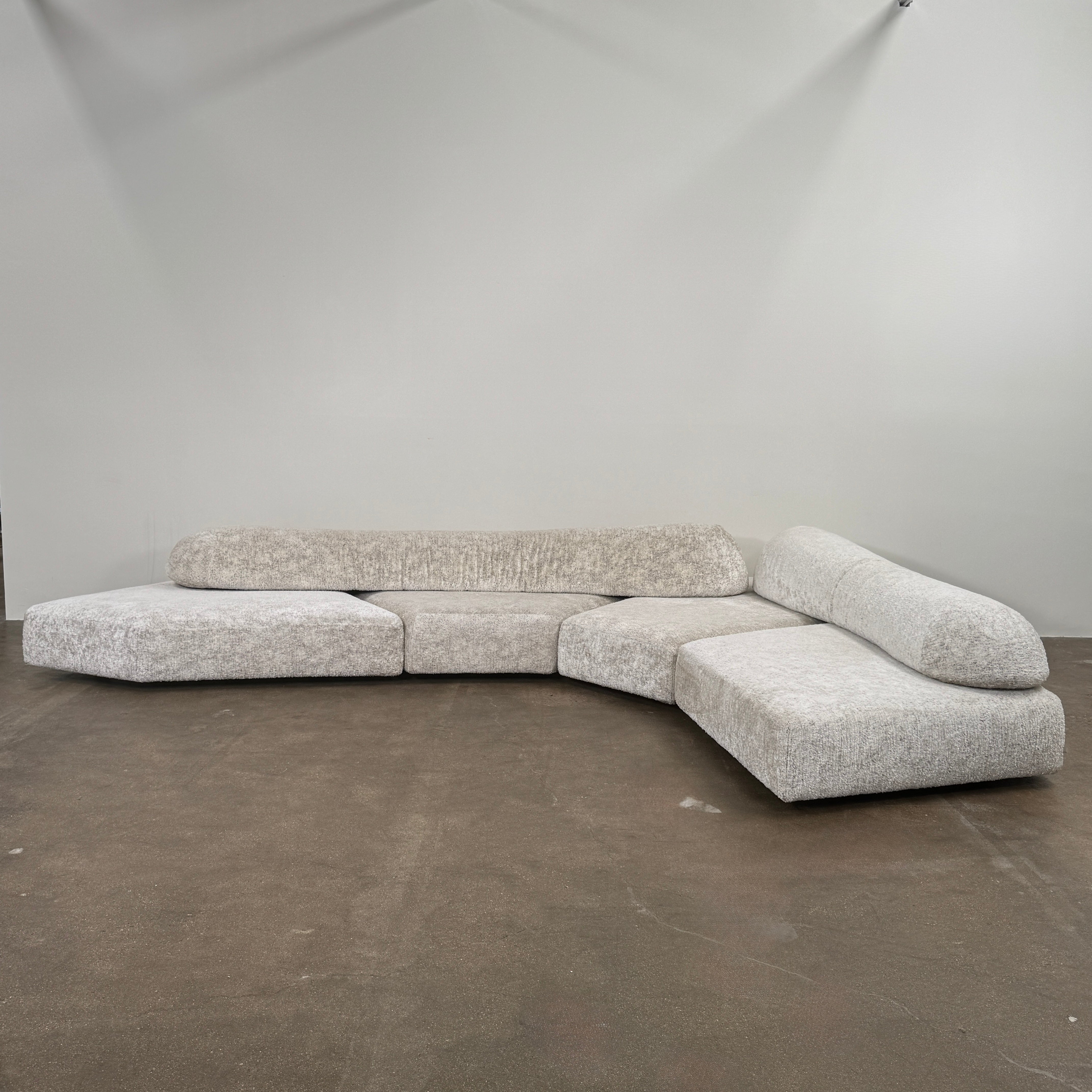 The Edra On The Rocks 4 piece Modular Sofa by Edra is a modern, light gray L-shaped sofa with customizable seating, featuring low rounded backrests and wide flat cushions, shown on a plain white background.