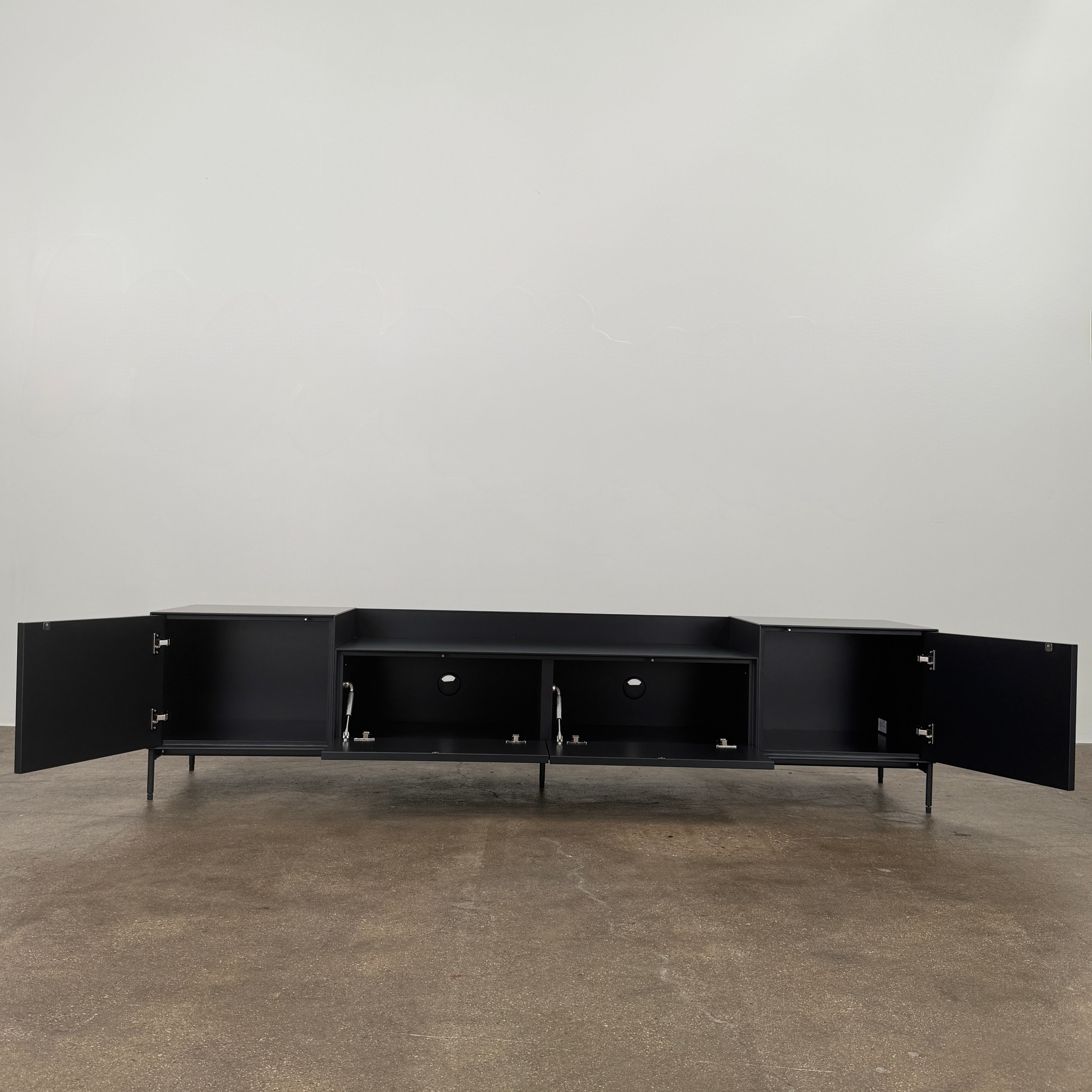The Treku Lauki Media Unit by Treku features a black minimalist design with two closed side cabinets, two central drawers, an open shelf, and built-in cord management on slim metal legs—perfect for modern spaces.