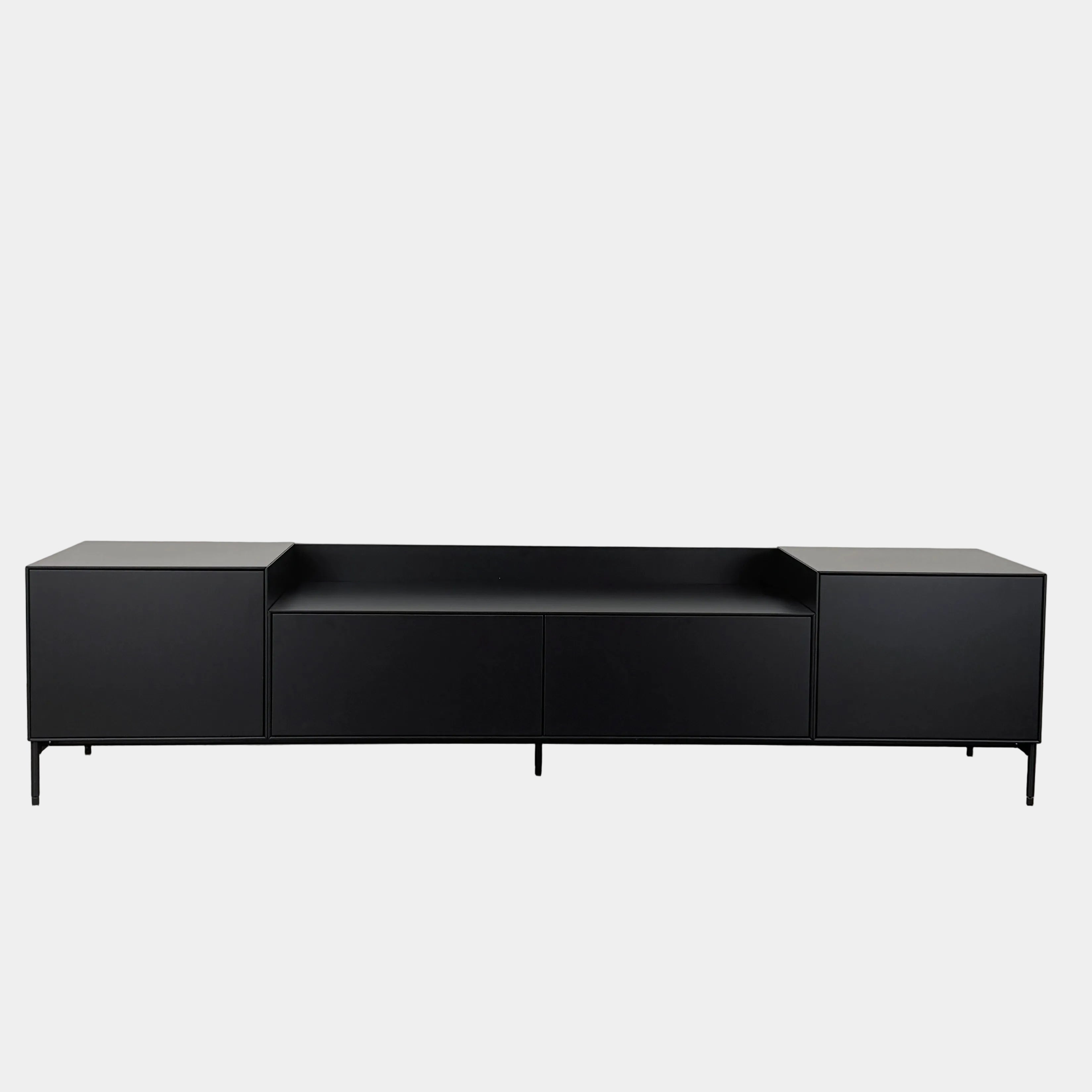 The Treku Lauki Media Unit by Treku features a black minimalist design with two closed side cabinets, two central drawers, an open shelf, and built-in cord management on slim metal legs—perfect for modern spaces.