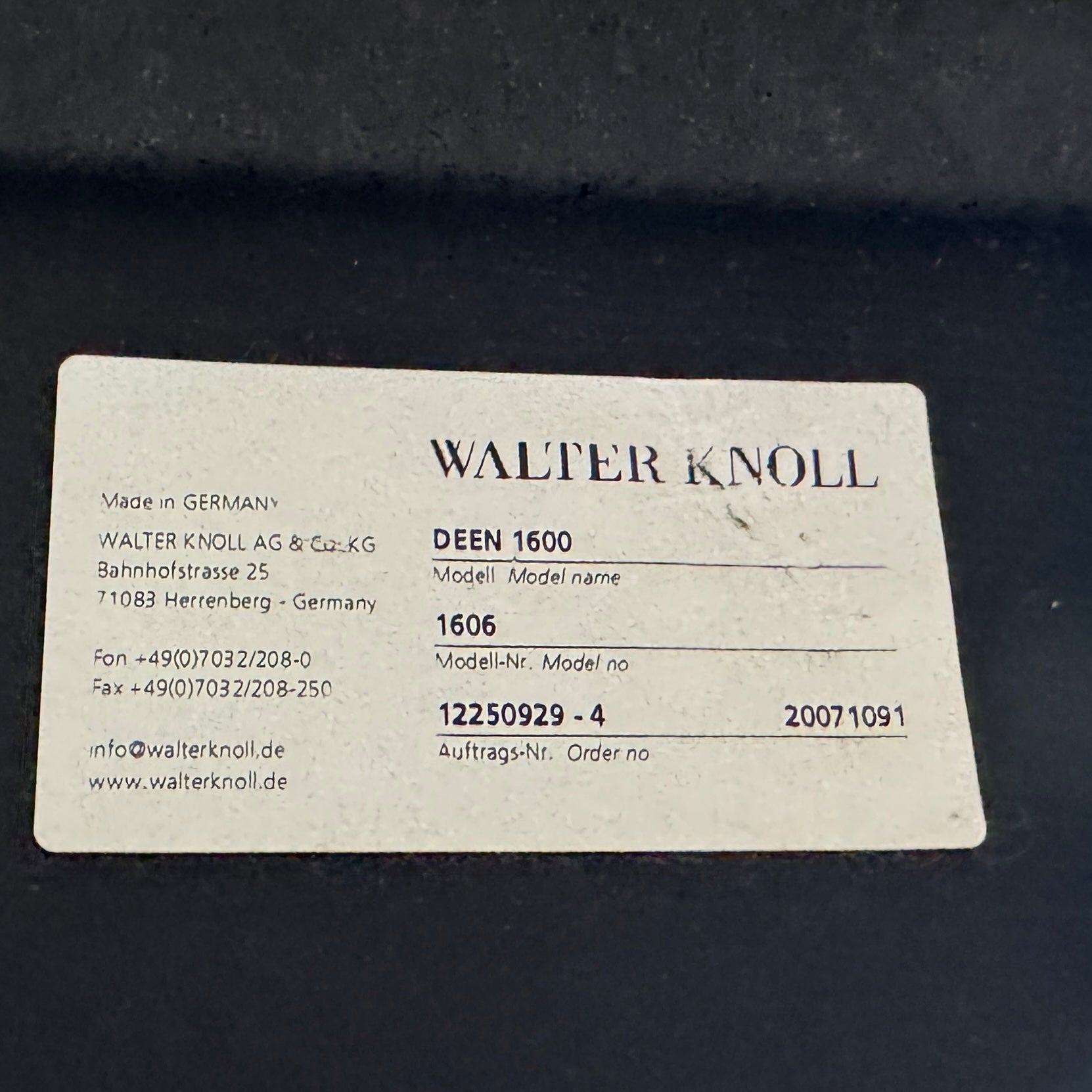 A set of Walter Knoll Deen Dining Chairs (2 armchairs, 8 side chairs) by Walter Knoll with beige upholstery and black legs are arranged in three rows on a brown concrete floor against a plain white wall.