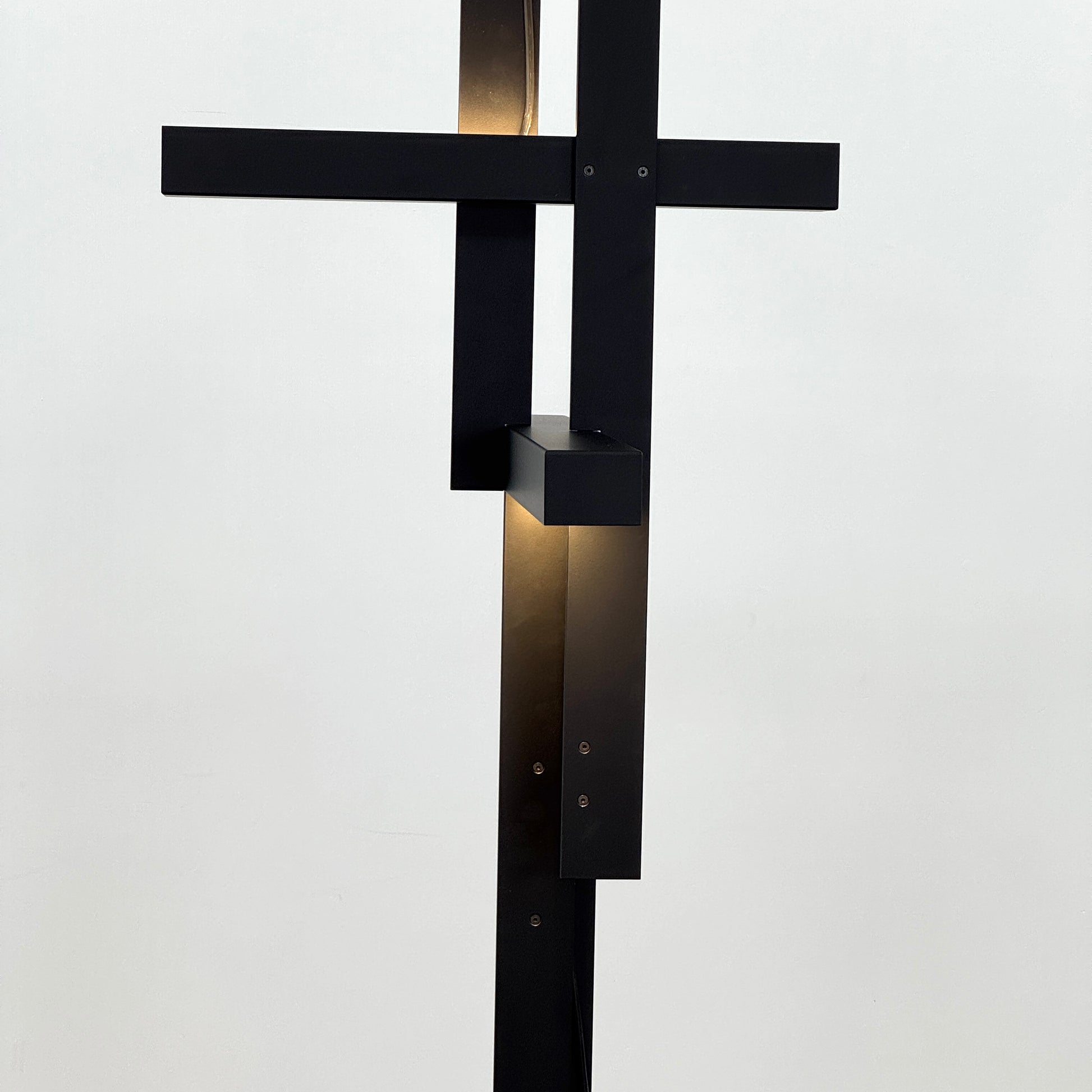 The Oluce LAS 376 LED Floor Lamp by Oluce features intersecting black rectangular panels on a flat base, with a visible power cord. Its sculptural design makes it a striking contemporary statement piece for any space.