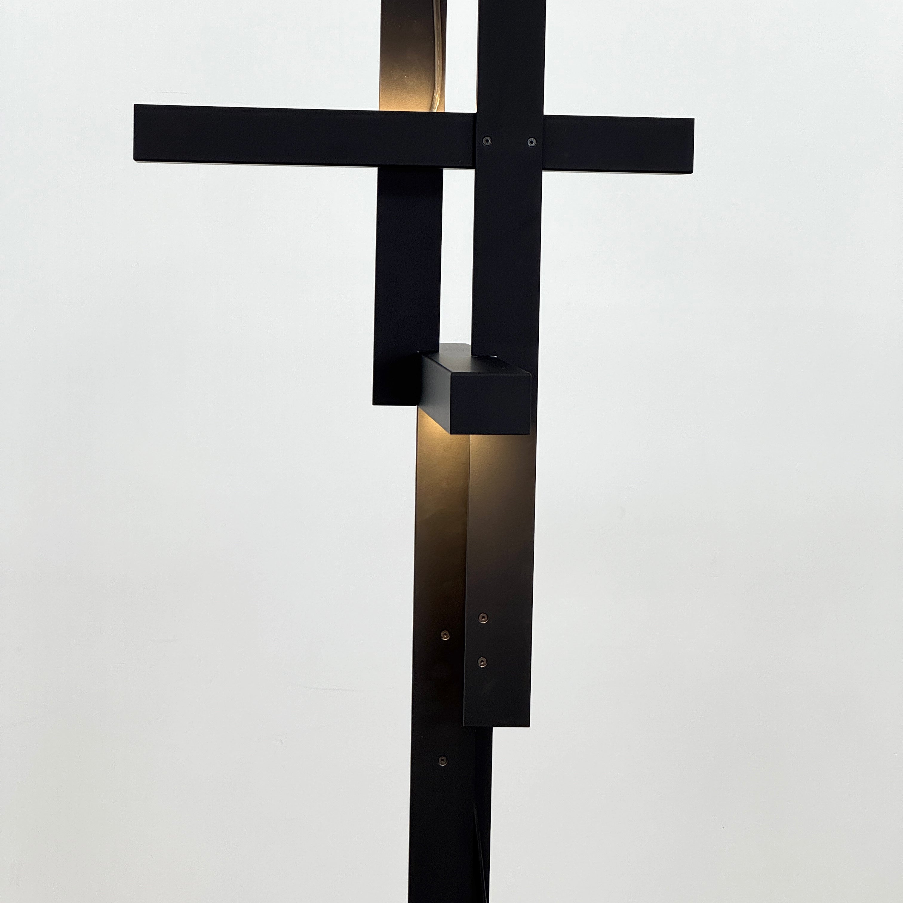 The Oluce LAS 376 LED Floor Lamp by Oluce features intersecting black rectangular panels on a flat base, with a visible power cord. Its sculptural design makes it a striking contemporary statement piece for any space.