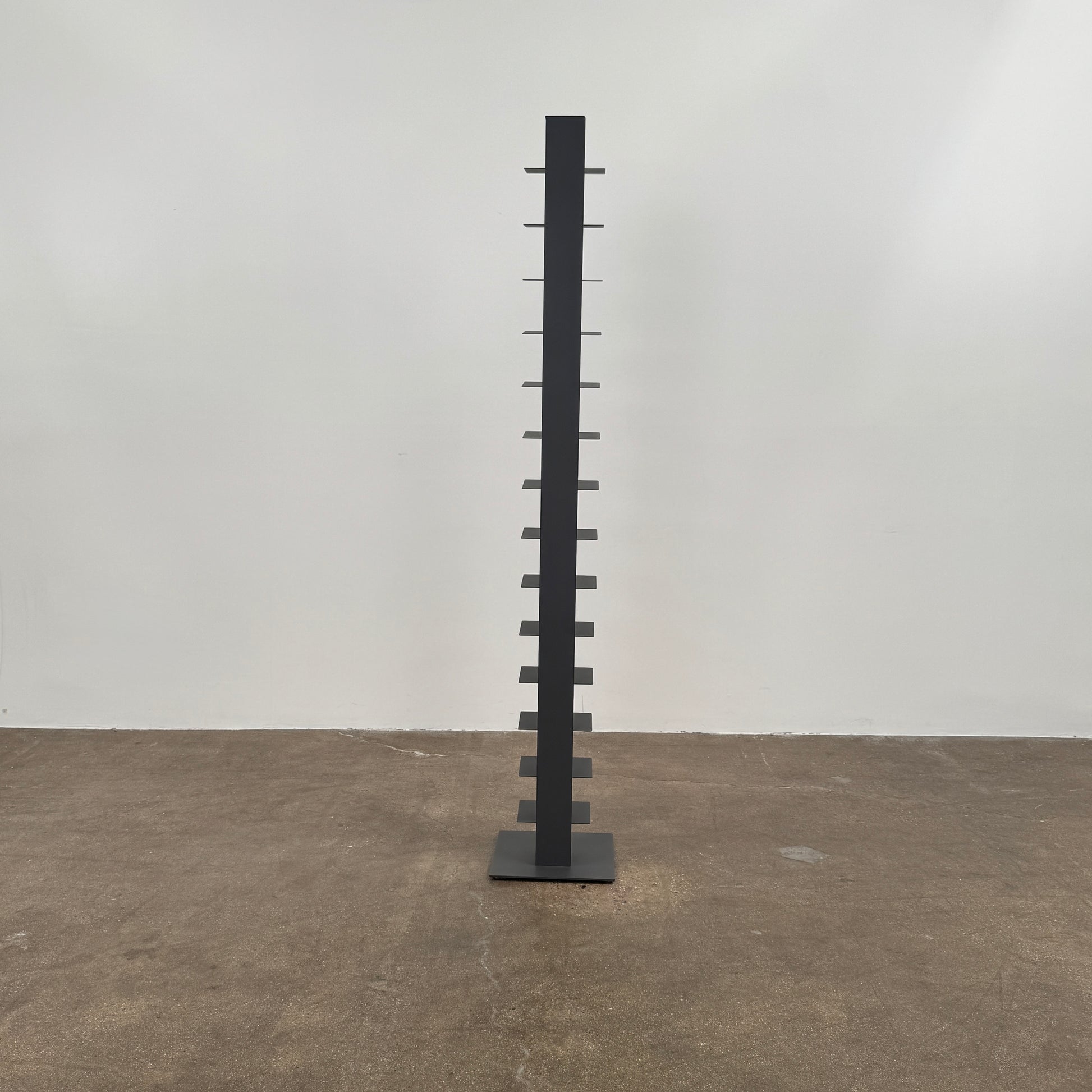 The DWR Story Bookcase by DWR is a tall, black, vertical metal bookcase with evenly spaced shelves and a square base—ideal for small-room storage and shown against a plain light background.