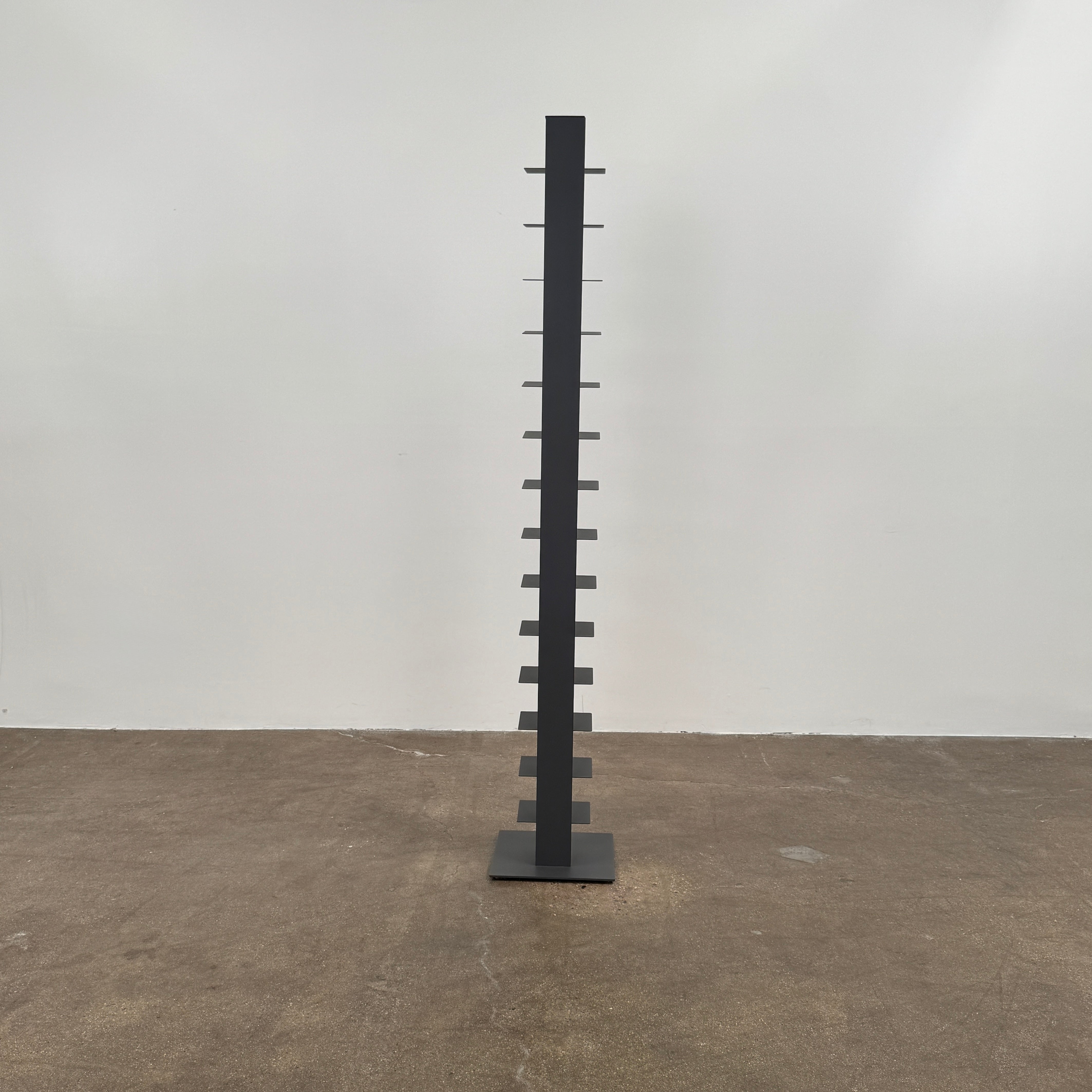 The DWR Story Bookcase by DWR is a tall, black, vertical metal bookcase with evenly spaced shelves and a square base—ideal for small-room storage and shown against a plain light background.