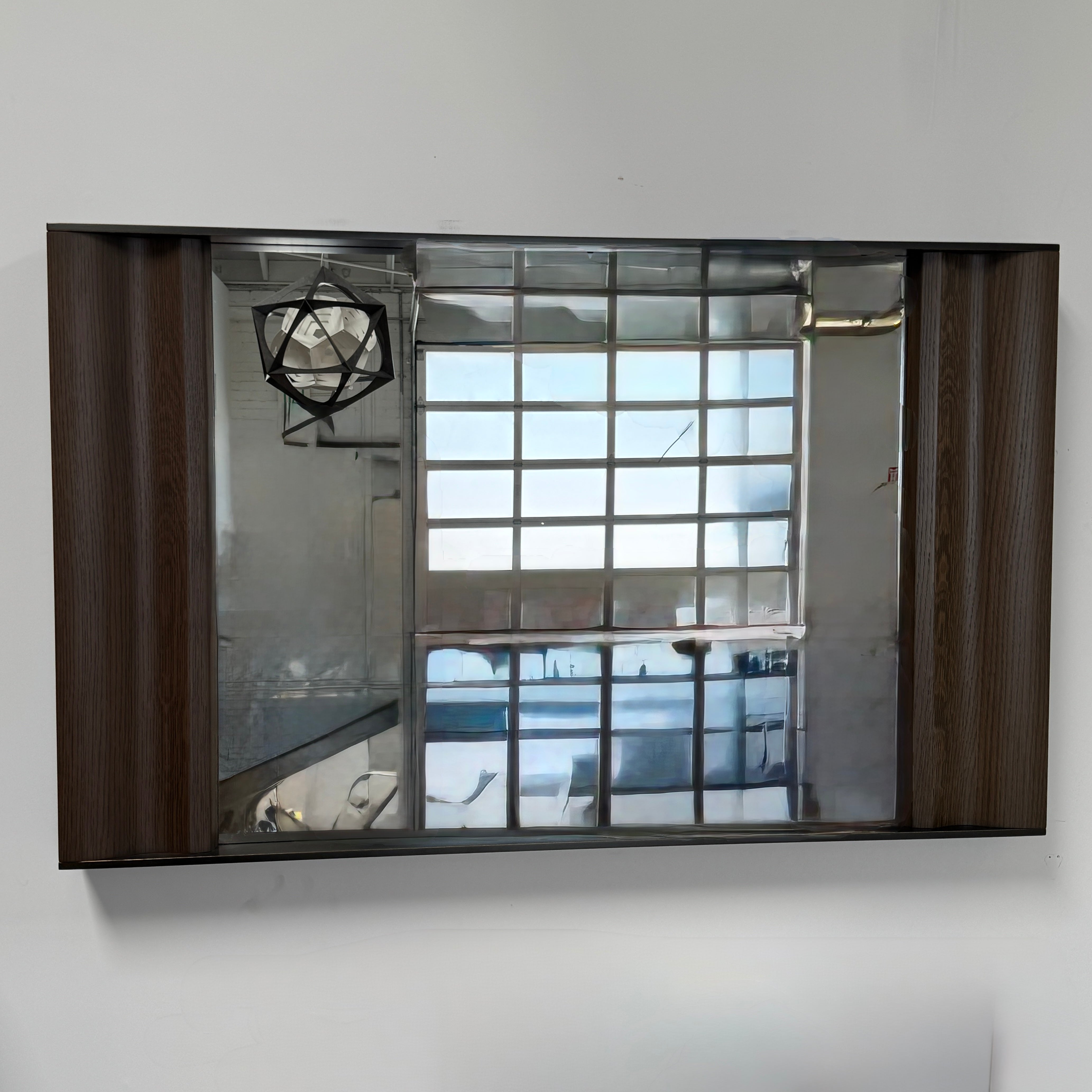 The Holly Hunt Cinema Mirror by Holly Hunt features a rectangular wooden frame, reflecting a grid window, pendant light, and interior, with a luxurious style true to its name.
