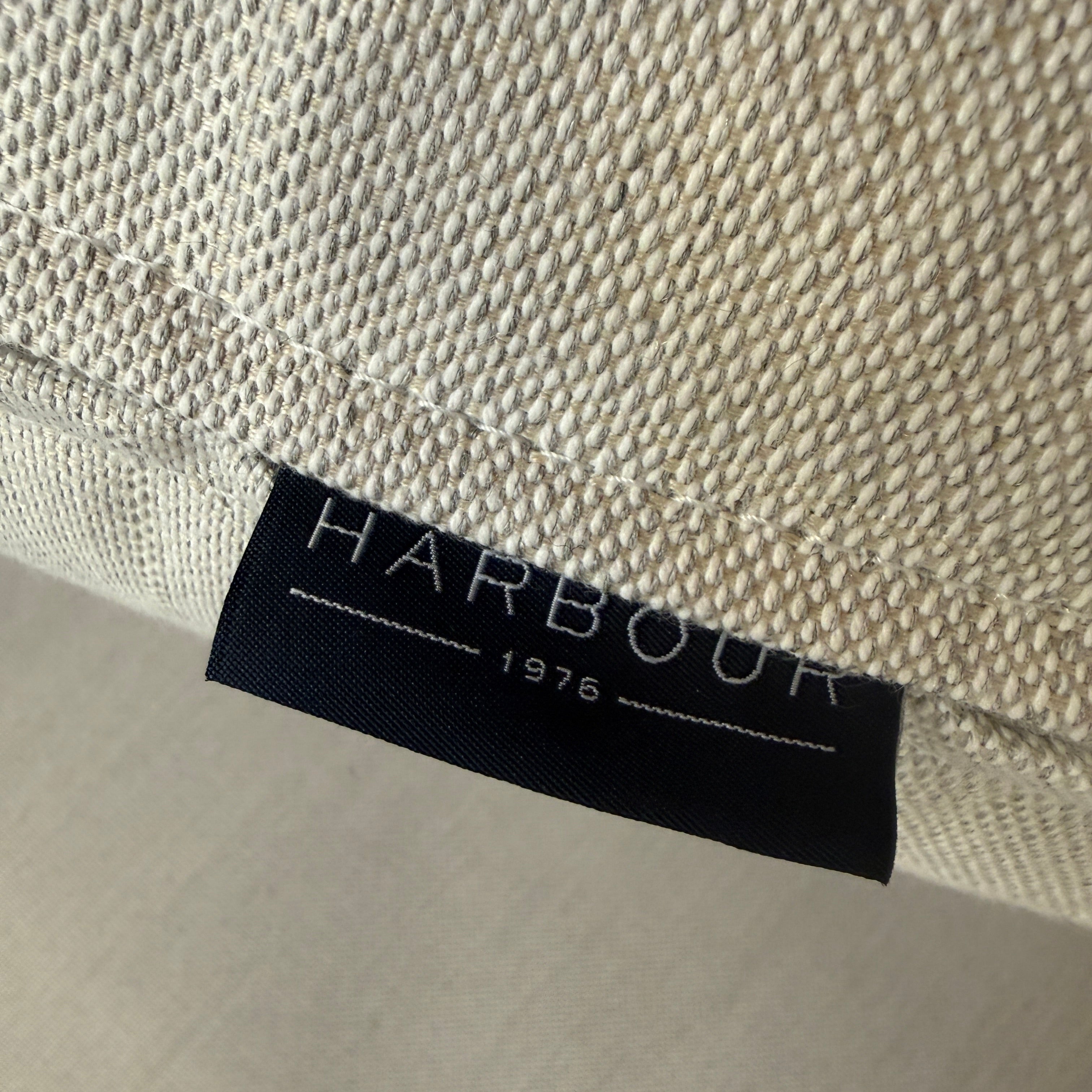 The Harbour Hayman Teak Outdoor Swivel Lounge Chair by Harbour features a modern design with a light beige cushion and a black-and-white patterned throw pillow, shown against a plain white background.