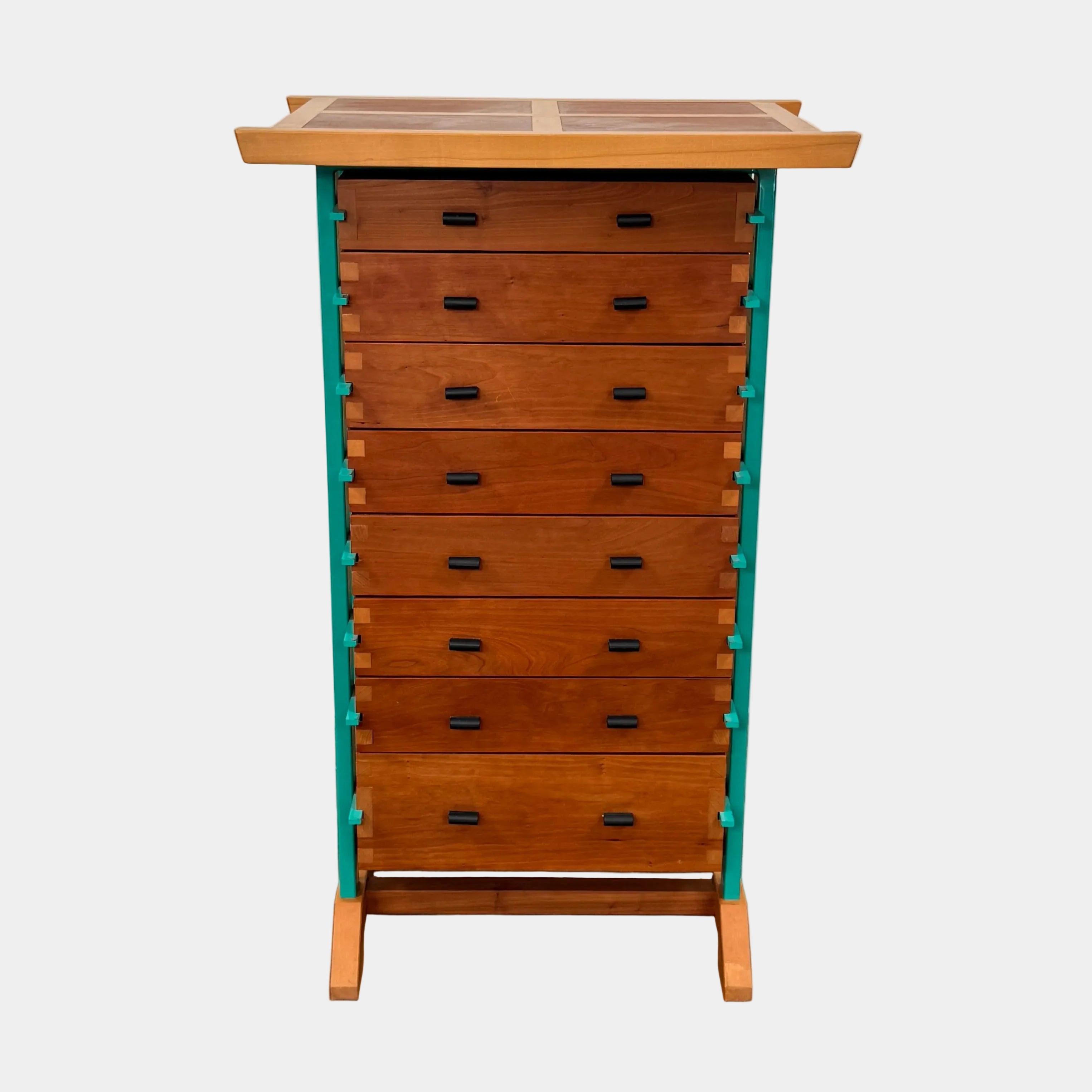 The Joseph Schwarte Tall Chest of Drawers by Artist features nine drawers, teal vertical side supports, black rectangular pulls, and a flat top—postmodern-inspired and shown against a plain background.