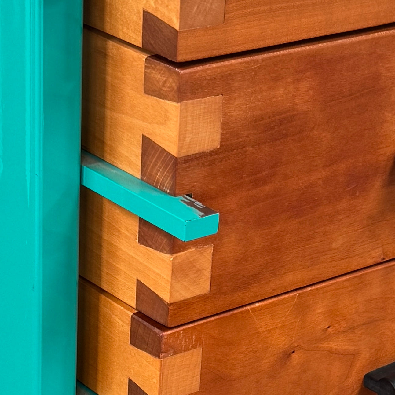 The Joseph Schwarte Tall Chest of Drawers by Artist features nine drawers, teal vertical side supports, black rectangular pulls, and a flat top—postmodern-inspired and shown against a plain background.