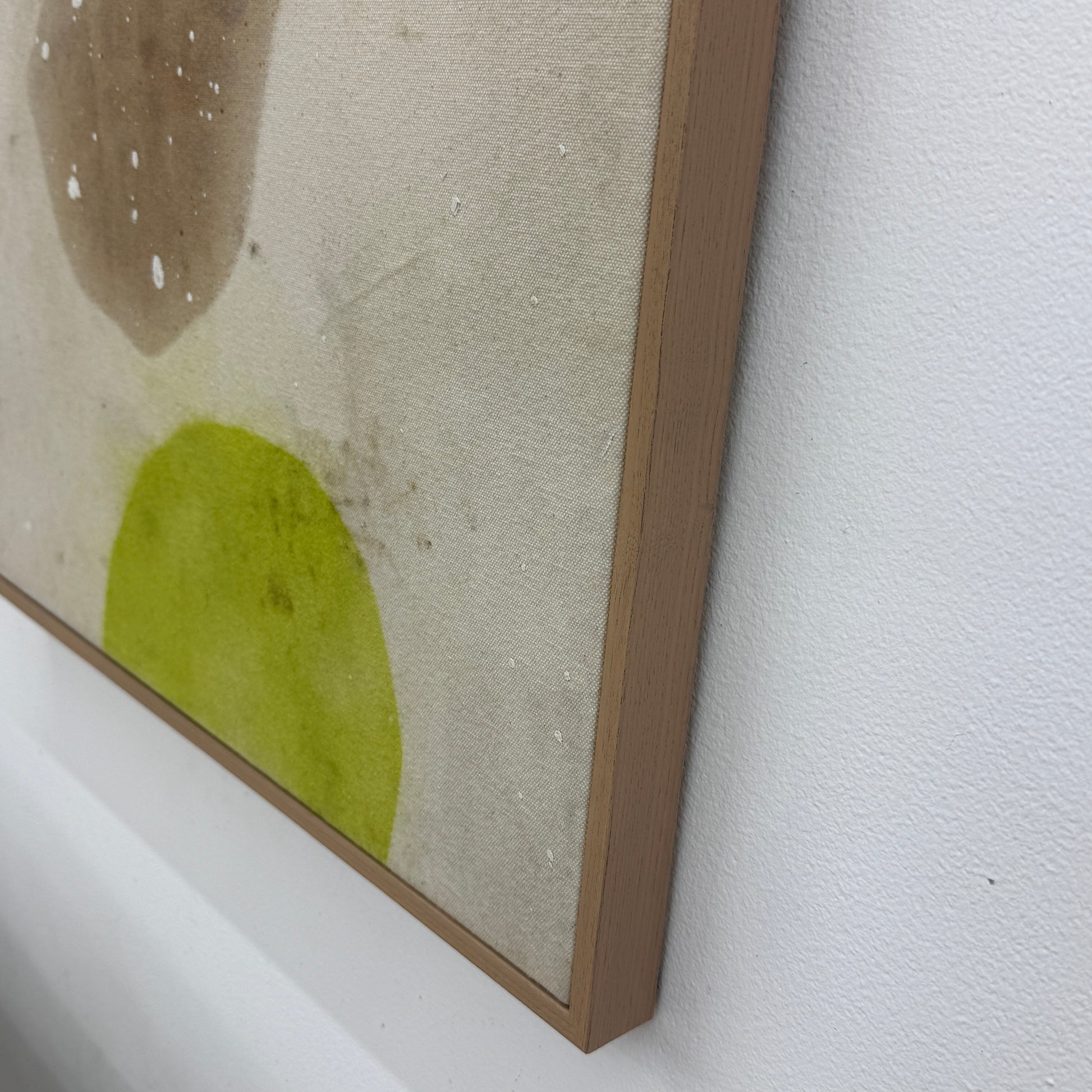 Framed Painting: Allison Caesar Mixed Media #2 - Untitled by Artist features abstract forms in brown and yellow-green with white splatters on a beige background, showcased in a thin frame.