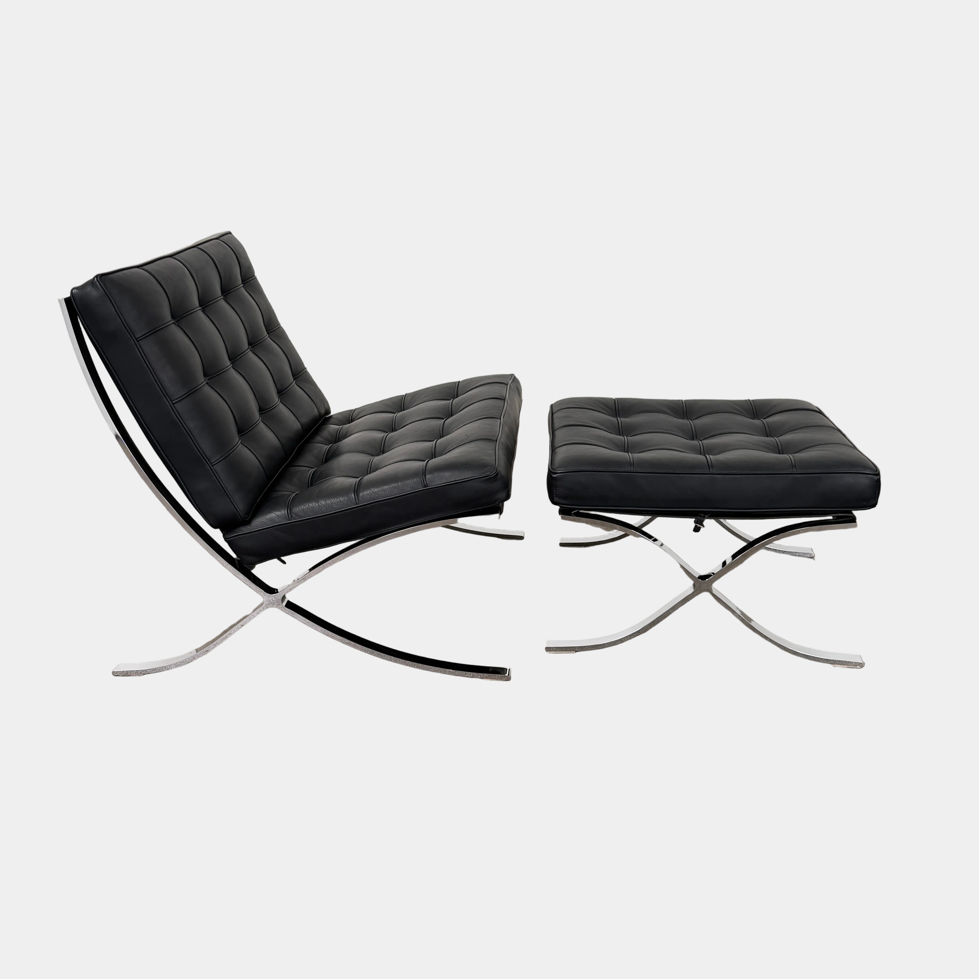 The Vintage DWR Barcelona Black Leather Chair & Ottoman by DWR features button-tufted cushions and chrome X-shaped legs, taking inspiration from the iconic Barcelona Chair, all presented against a plain white background.