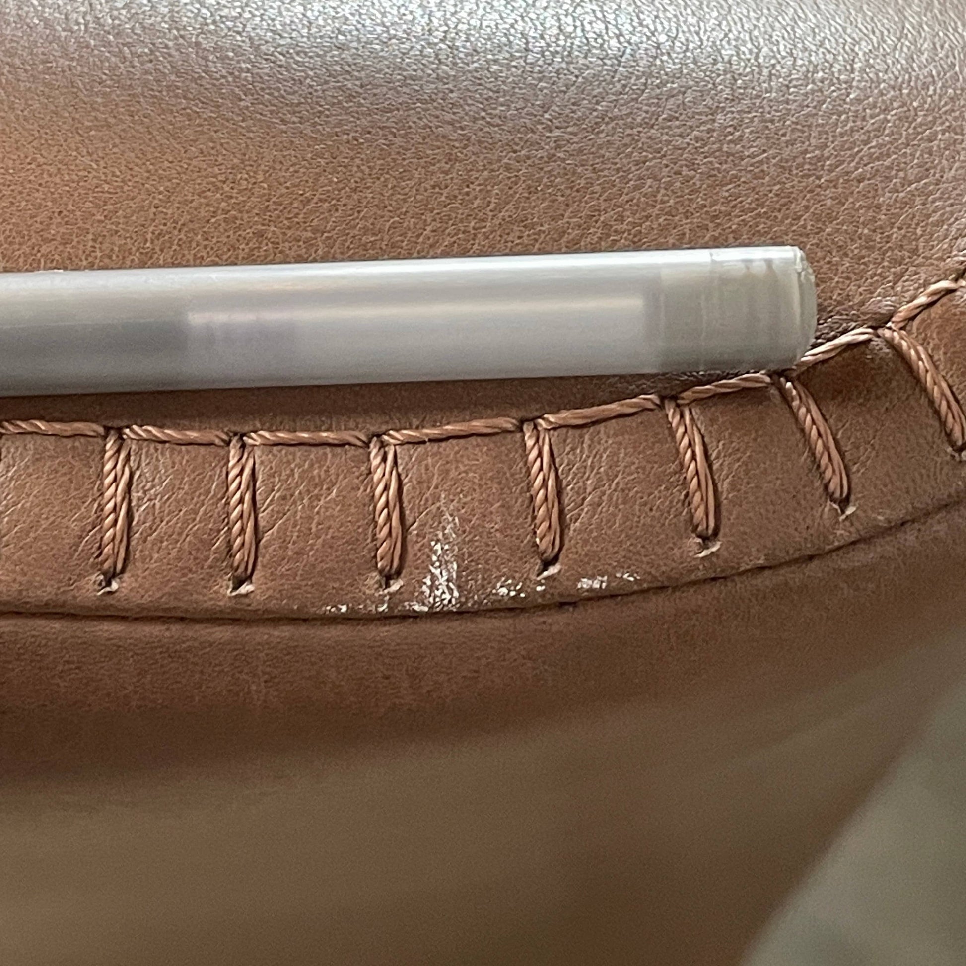 A brown leather armchair with a high backrest and curved arms, showcasing classic leather upholstery, is paired with a matching ottoman, both resting on thin legs. This sophisticated set embodies the elegant style of Maxalto's Maxalto Febo High Back Lounge Chair and Ottoman collection.