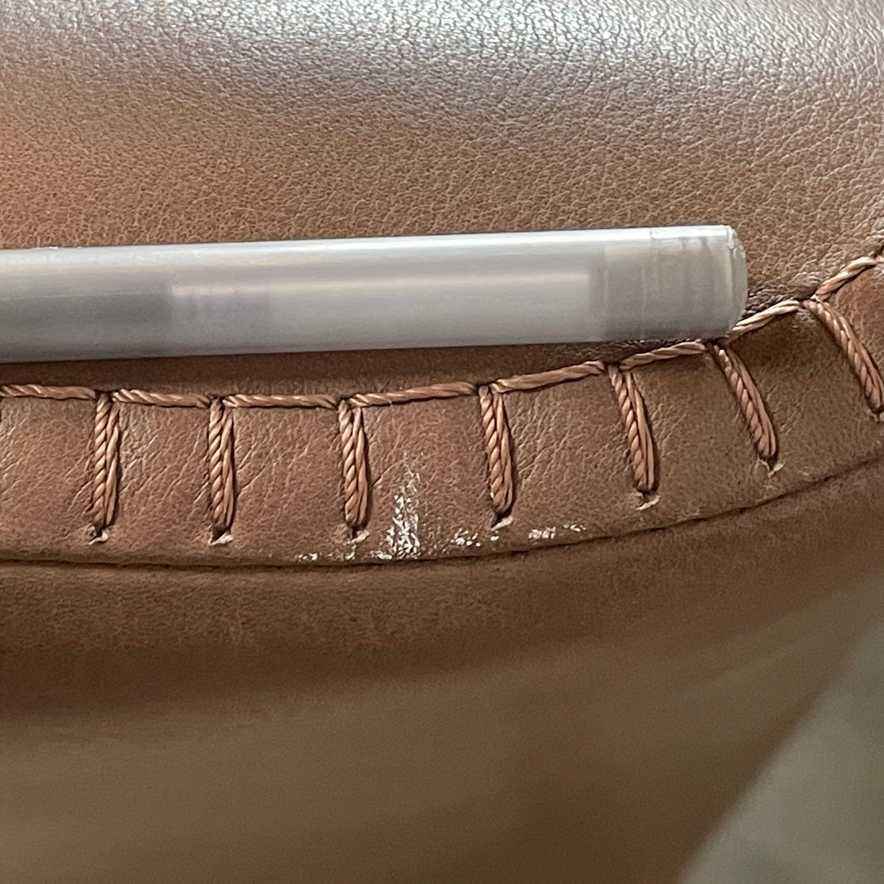 A brown leather armchair with a high backrest and curved arms, showcasing classic leather upholstery, is paired with a matching ottoman, both resting on thin legs. This sophisticated set embodies the elegant style of Maxalto's Maxalto Febo High Back Lounge Chair and Ottoman collection.