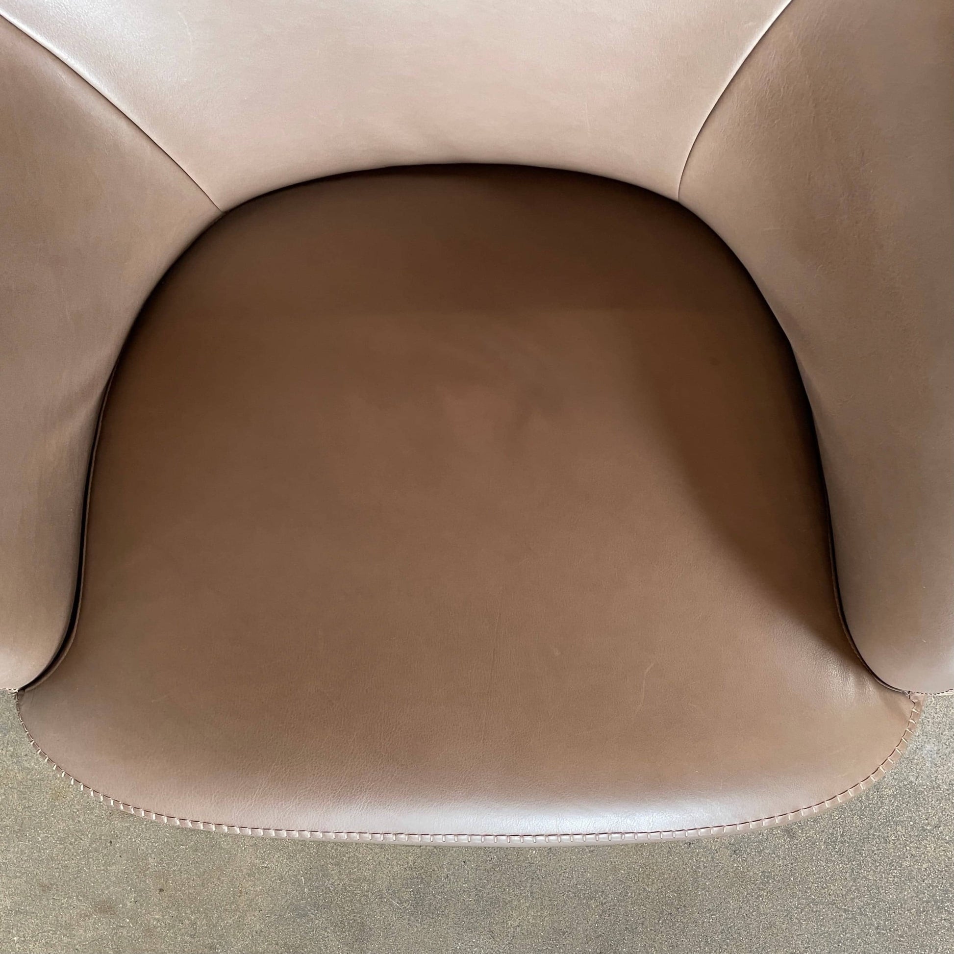 A brown leather armchair with a high backrest and curved arms, showcasing classic leather upholstery, is paired with a matching ottoman, both resting on thin legs. This sophisticated set embodies the elegant style of Maxalto's Maxalto Febo High Back Lounge Chair and Ottoman collection.
