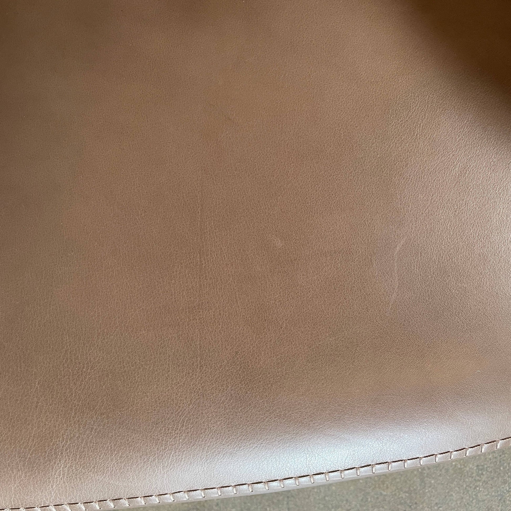 A brown leather armchair with a high backrest and curved arms, showcasing classic leather upholstery, is paired with a matching ottoman, both resting on thin legs. This sophisticated set embodies the elegant style of Maxalto's Maxalto Febo High Back Lounge Chair and Ottoman collection.