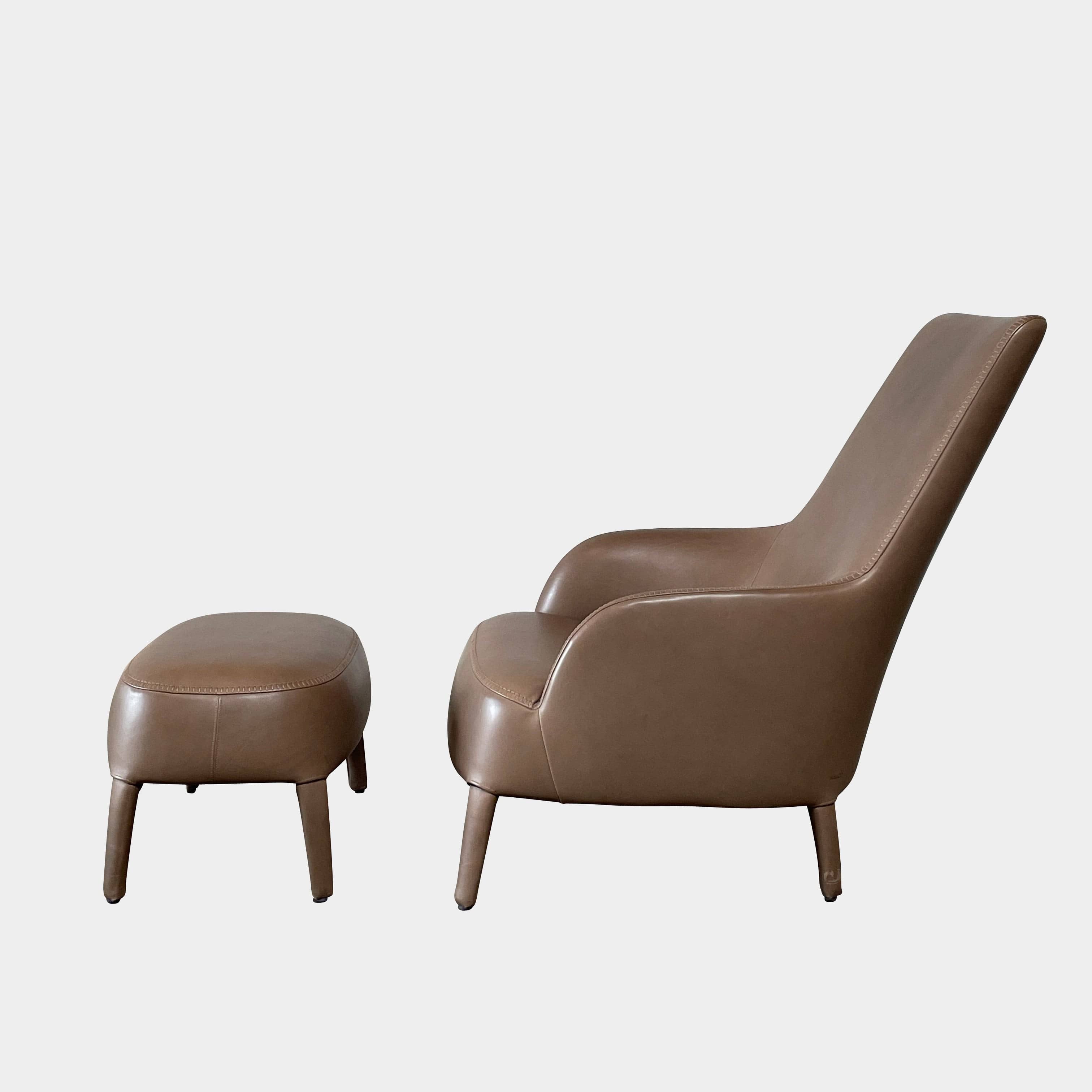 A brown leather armchair with a high backrest and curved arms, showcasing classic leather upholstery, is paired with a matching ottoman, both resting on thin legs. This sophisticated set embodies the elegant style of Maxalto's Maxalto Febo High Back Lounge Chair and Ottoman collection.