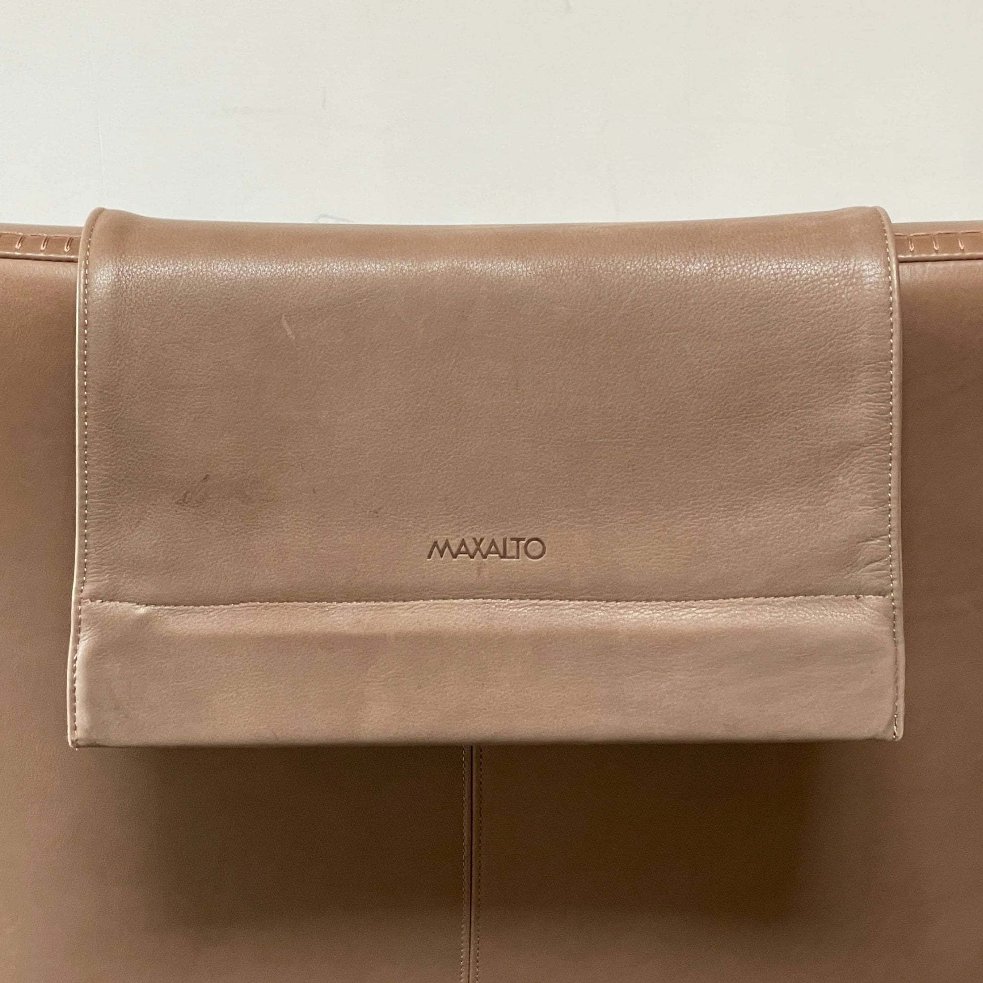 A brown leather armchair with a high backrest and curved arms, showcasing classic leather upholstery, is paired with a matching ottoman, both resting on thin legs. This sophisticated set embodies the elegant style of Maxalto's Maxalto Febo High Back Lounge Chair and Ottoman collection.