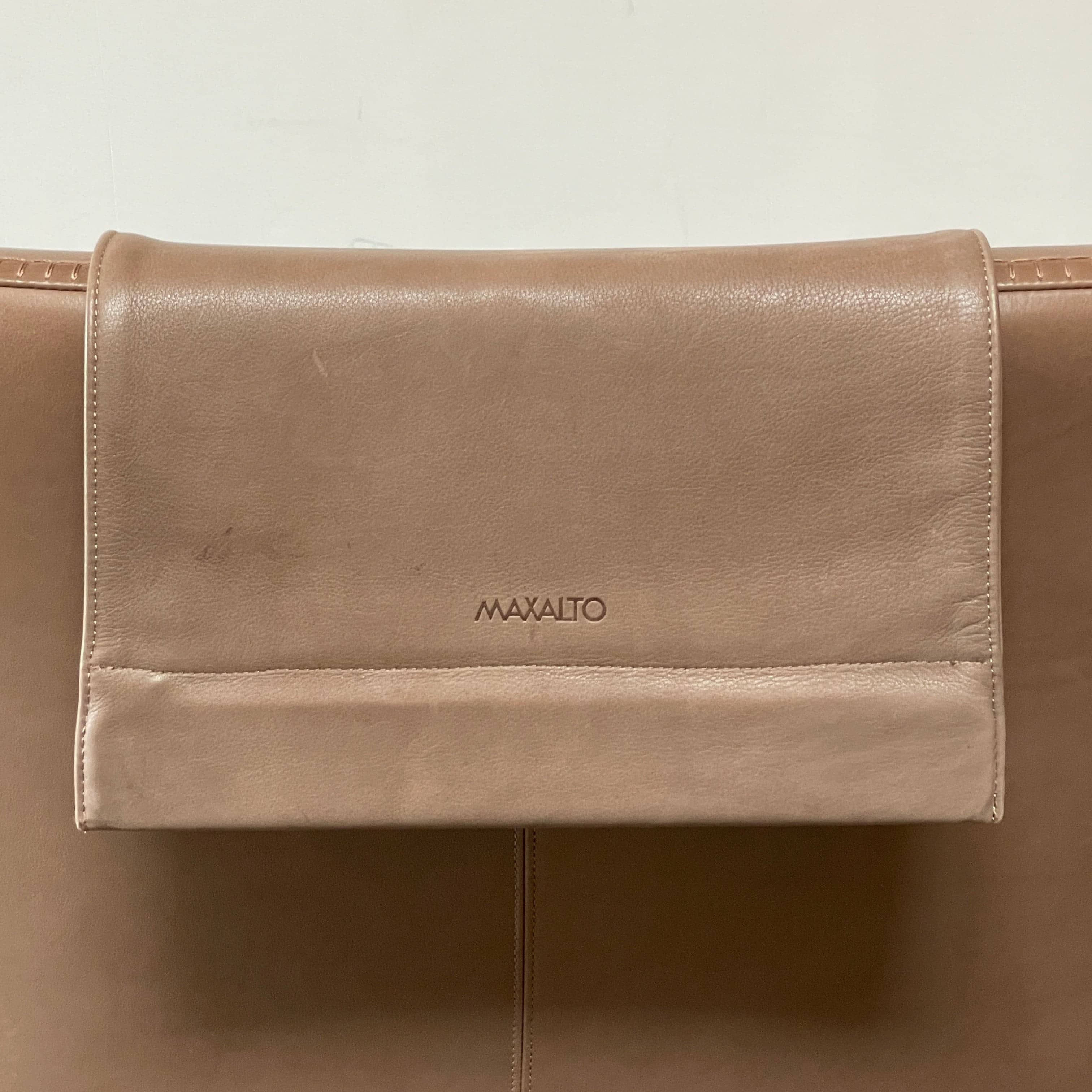 A brown leather armchair with a high backrest and curved arms, showcasing classic leather upholstery, is paired with a matching ottoman, both resting on thin legs. This sophisticated set embodies the elegant style of Maxalto's Maxalto Febo High Back Lounge Chair and Ottoman collection.