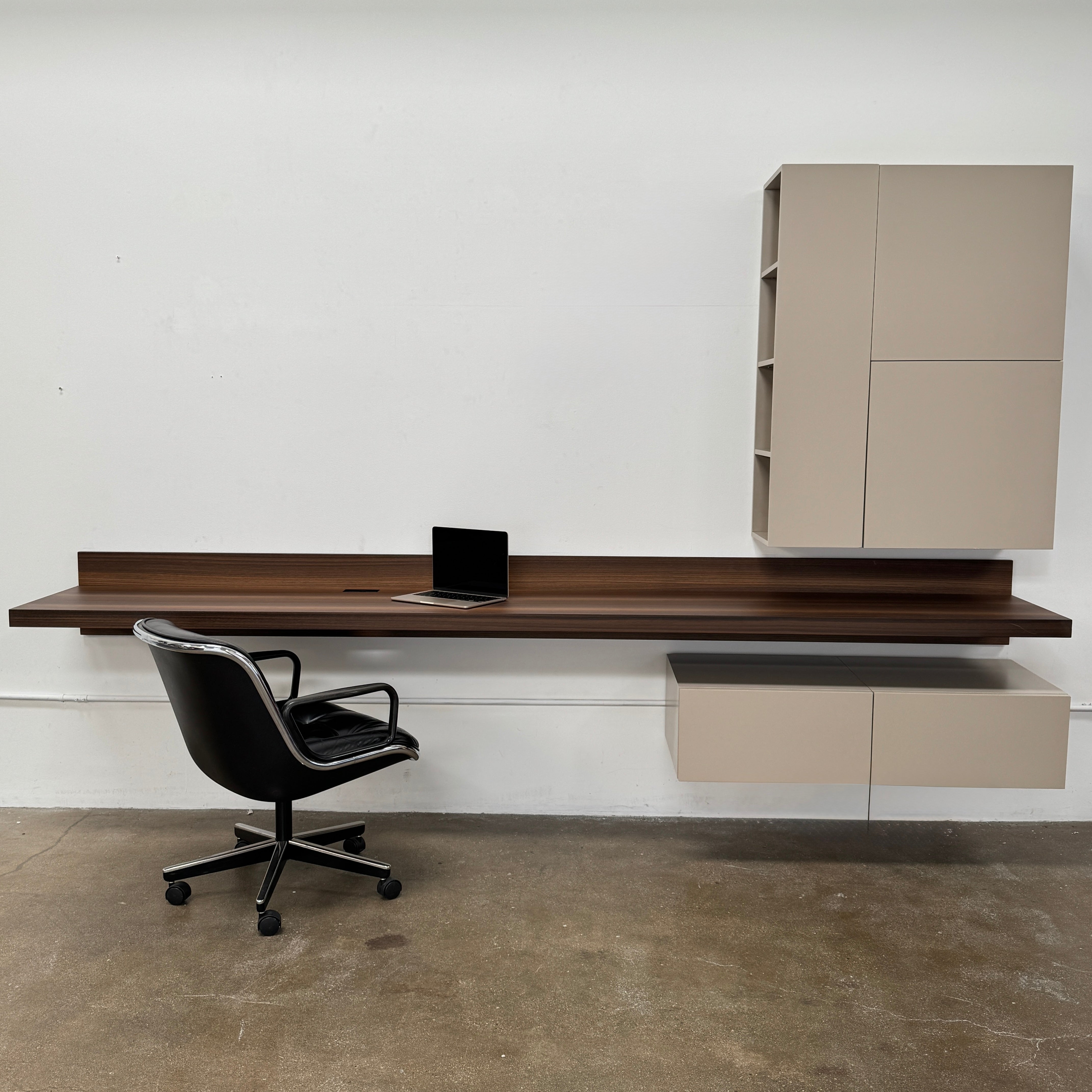 The Molteni & C Fortepiano Wall-mounted Desk System features a long wooden shelf, beige storage cabinets, and drawers for a sleek, modern look against a white wall.