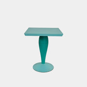 The Vintage Kartell Miss Balu Table by Kartell is a small, square turquoise plastic table with a central pedestal and round base, shown on a plain white background.