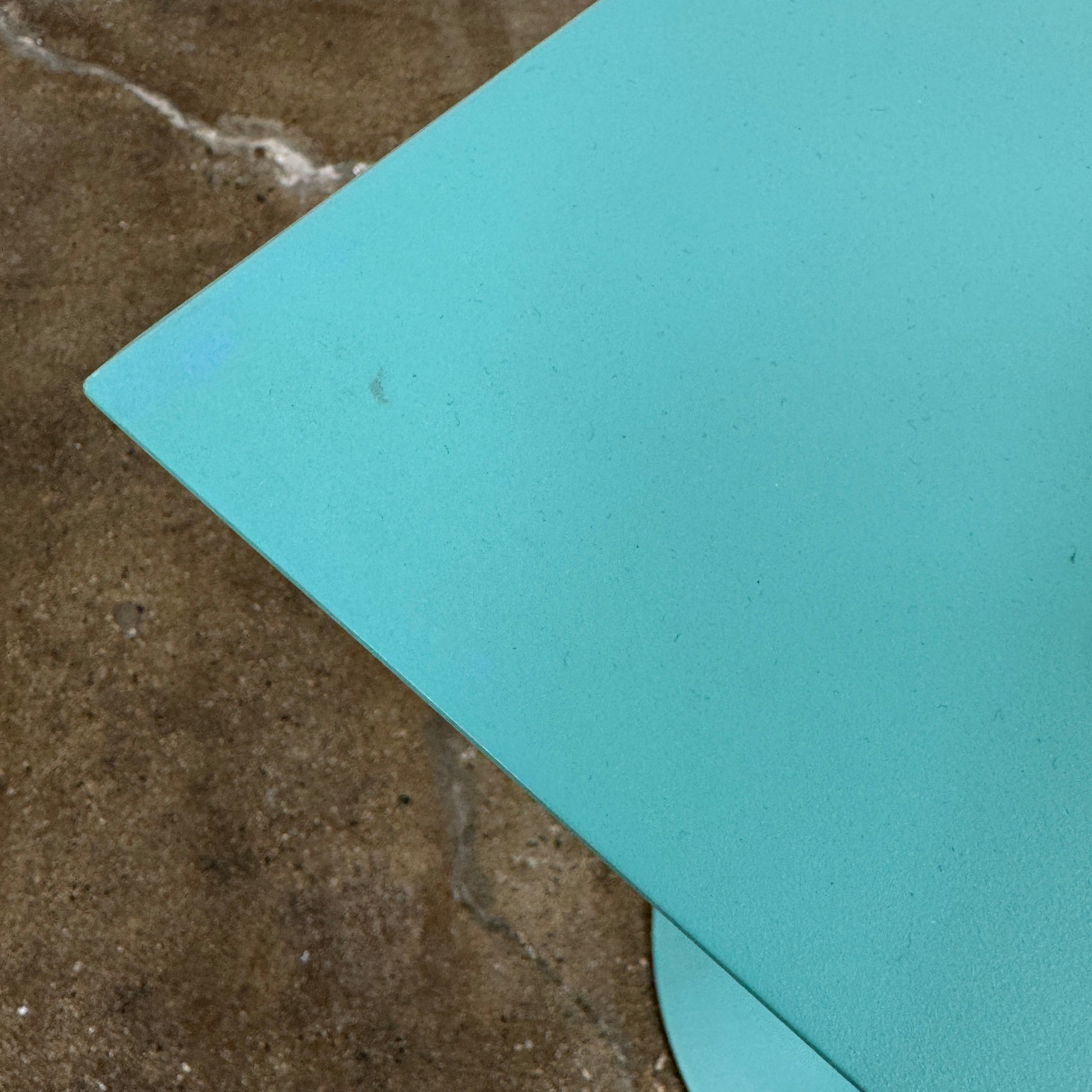 The Vintage Kartell Miss Balu Table by Kartell is a small, square turquoise plastic table with a central pedestal and round base, shown on a plain white background.