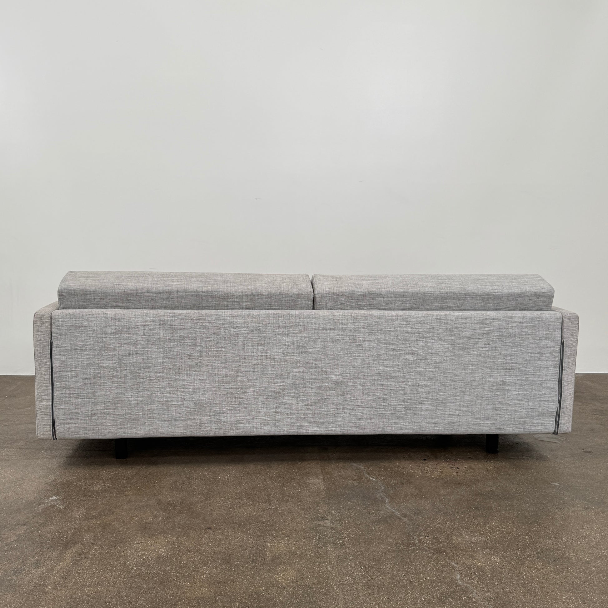The DWR Tuck Sleeper Sofa by DWR features modern light gray fabric, straight arms, and black legs—ideal for a guest room. Shown against a plain white background.