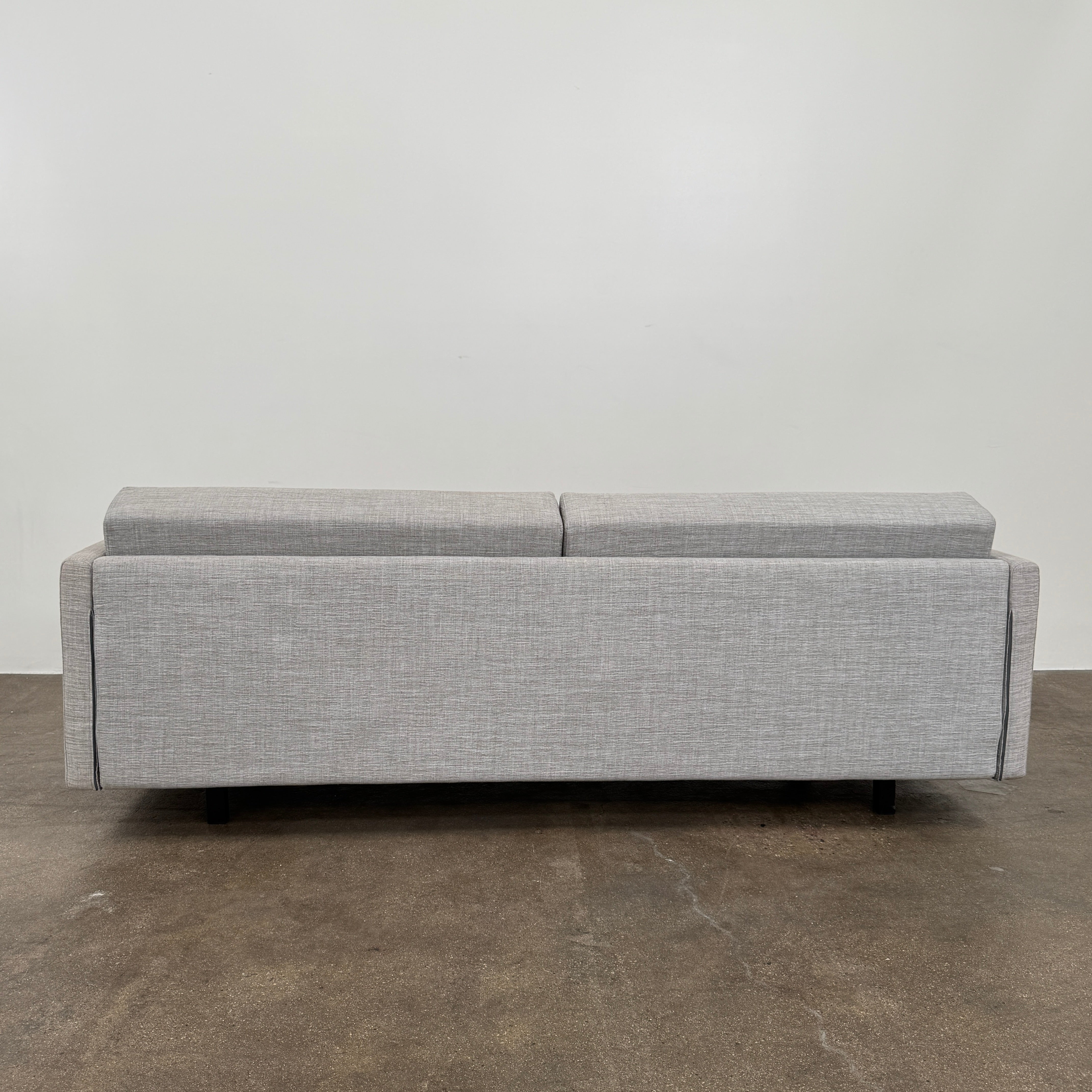 The DWR Tuck Sleeper Sofa by DWR features modern light gray fabric, straight arms, and black legs—ideal for a guest room. Shown against a plain white background.