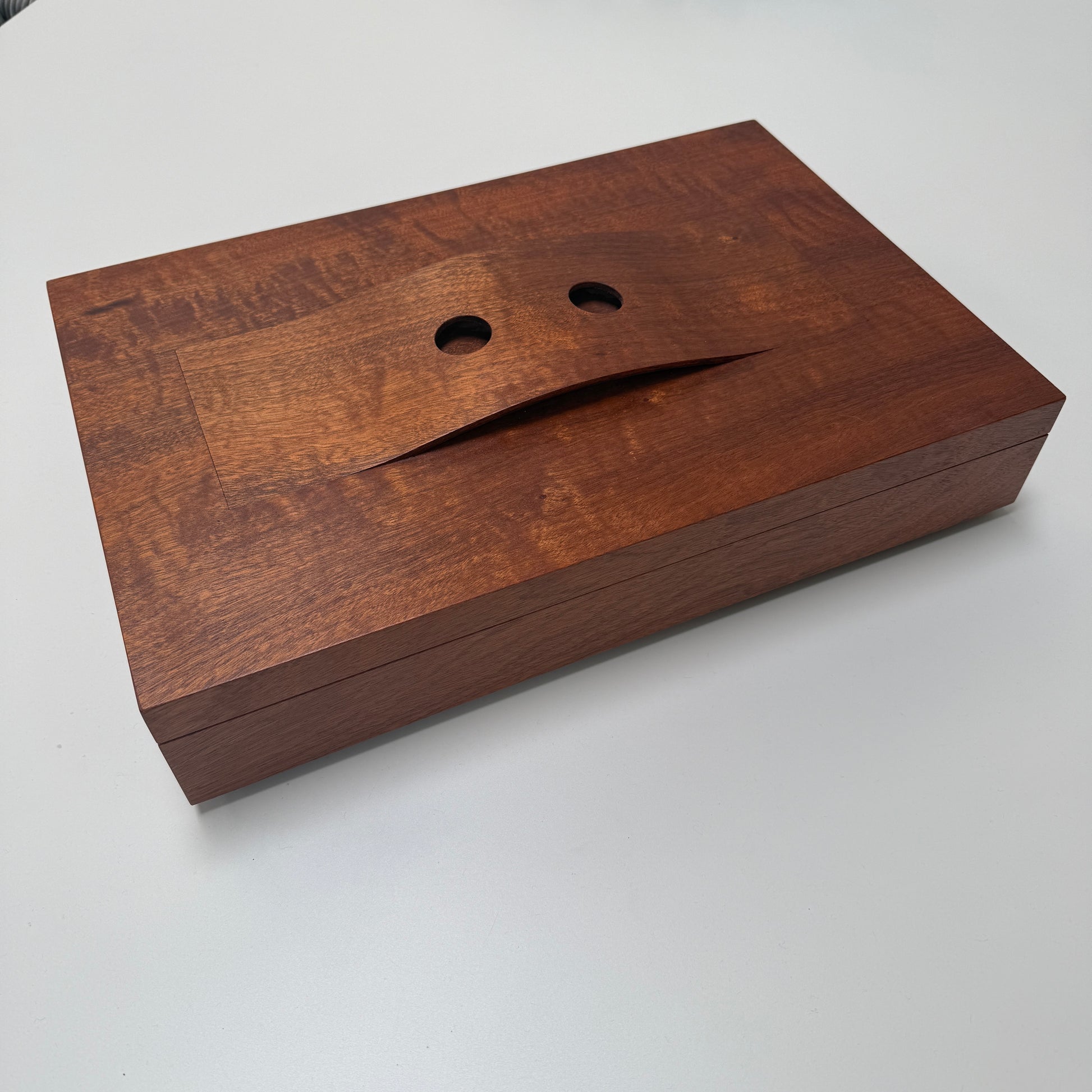 The Mike Fair Jewelry / Cigar Box by Mike Fair Custom Furnishings is a rectangular handcrafted box with a lid featuring a curved cutout and two circular holes, displayed against a plain white background.