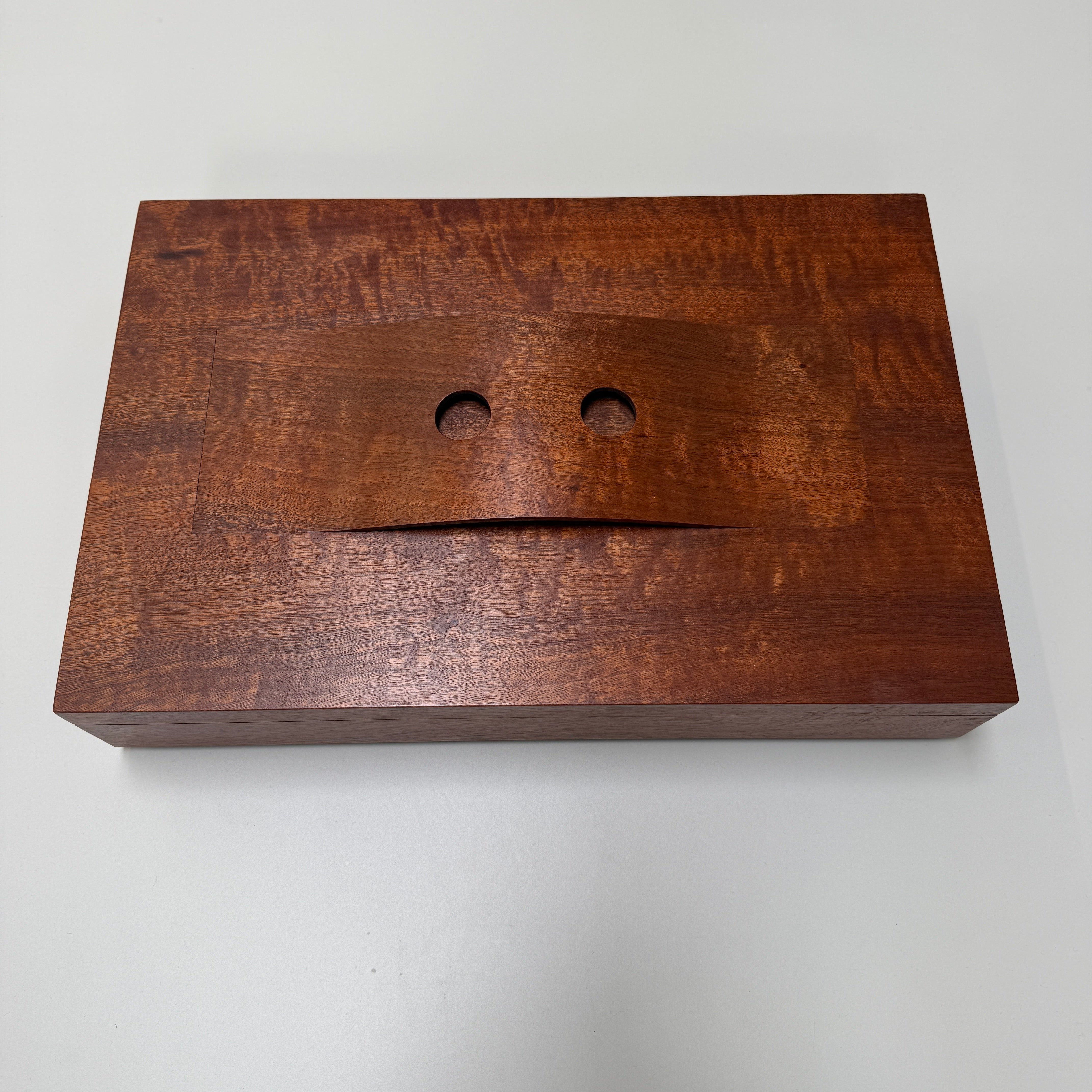 The Mike Fair Jewelry / Cigar Box by Mike Fair Custom Furnishings is a rectangular handcrafted box with a lid featuring a curved cutout and two circular holes, displayed against a plain white background.