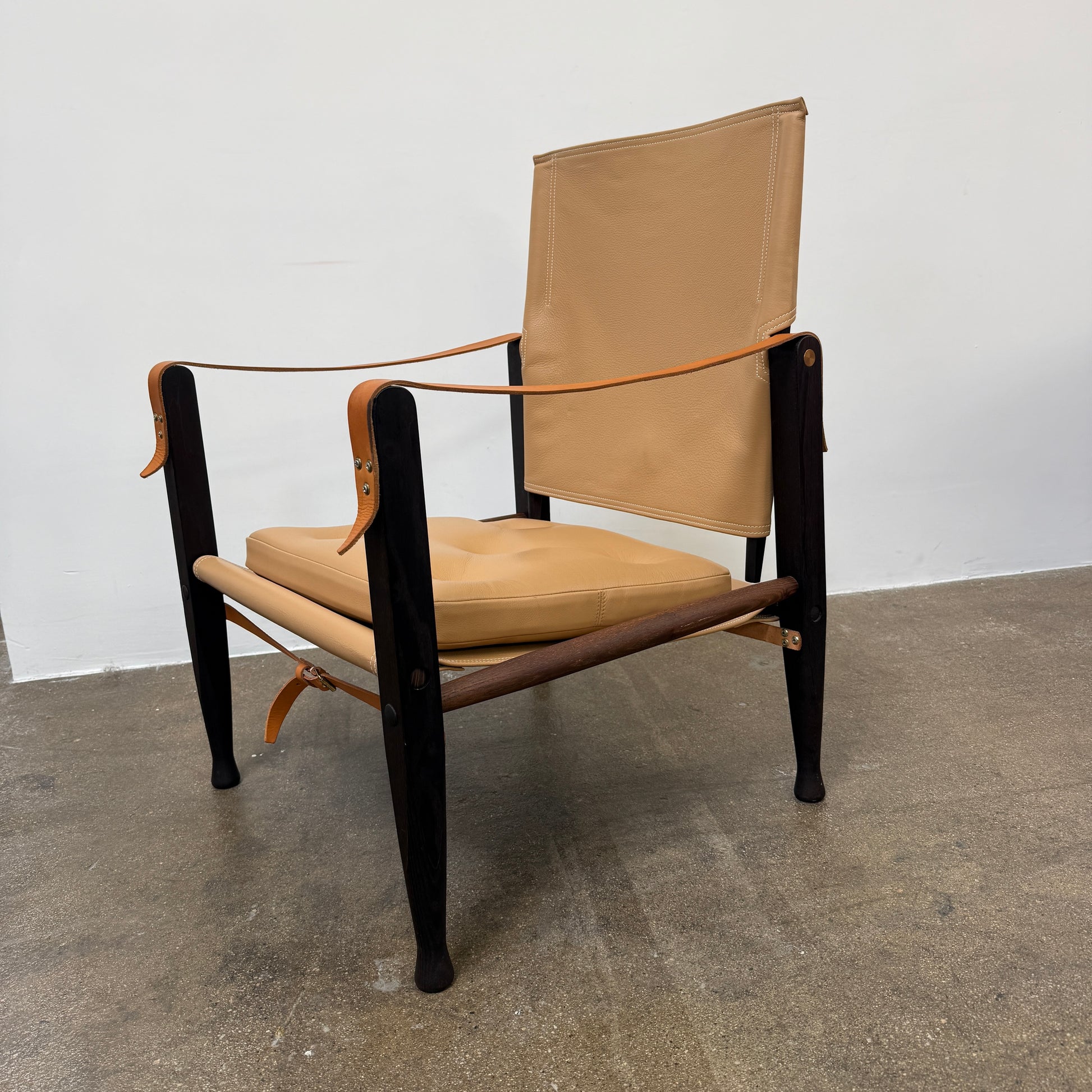 The Carl Hansen & Son KK47000 Safari Lounge Chair by Kaare Klint features canvas and leather with wooden legs and armrests, shown from the front on a plain white background.