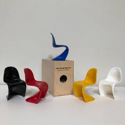A set of plastic Vitra Miniatures Panton Chairs with a box in front.