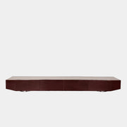 The Minotti Jason Sideboard by Minotti is a long, low-profile, dark brown modern piece with four doors, shown against a white wall on a polished concrete floor.