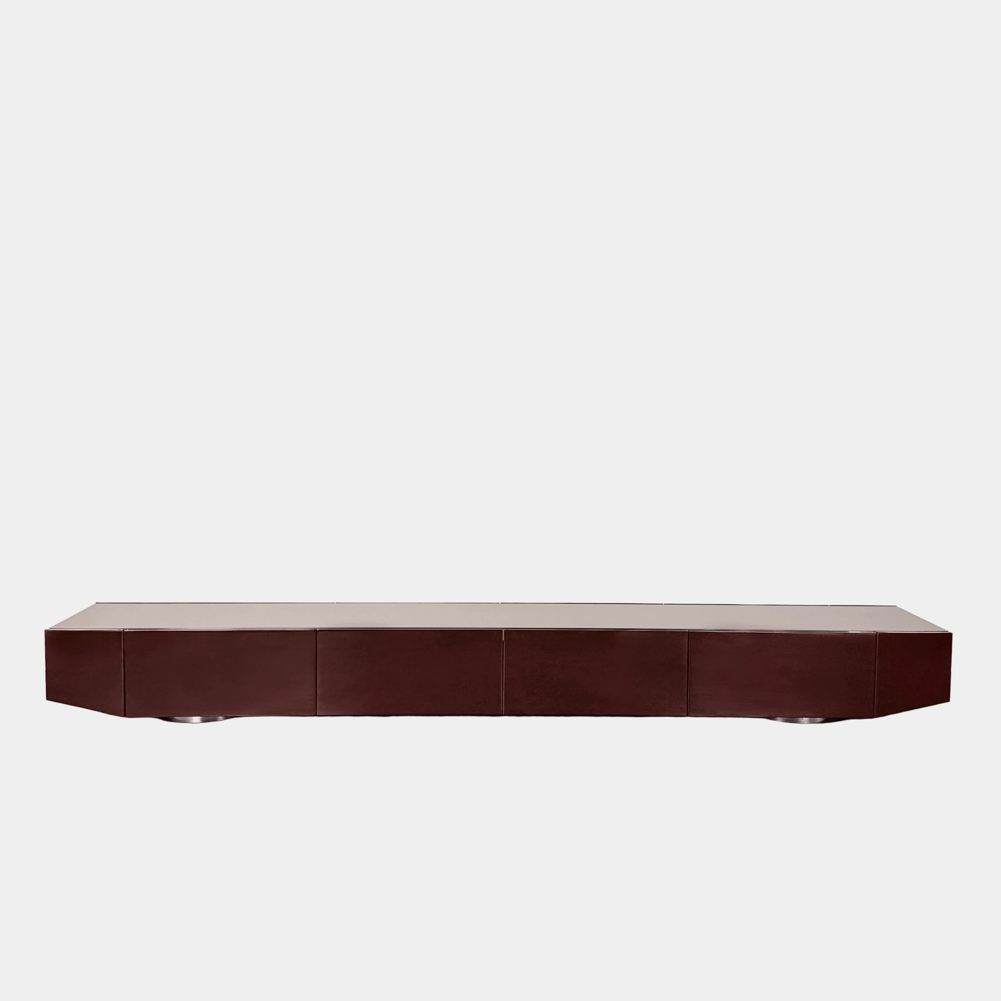 The Minotti Jason Sideboard by Minotti is a long, low-profile, dark brown modern piece with four doors, shown against a white wall on a polished concrete floor.