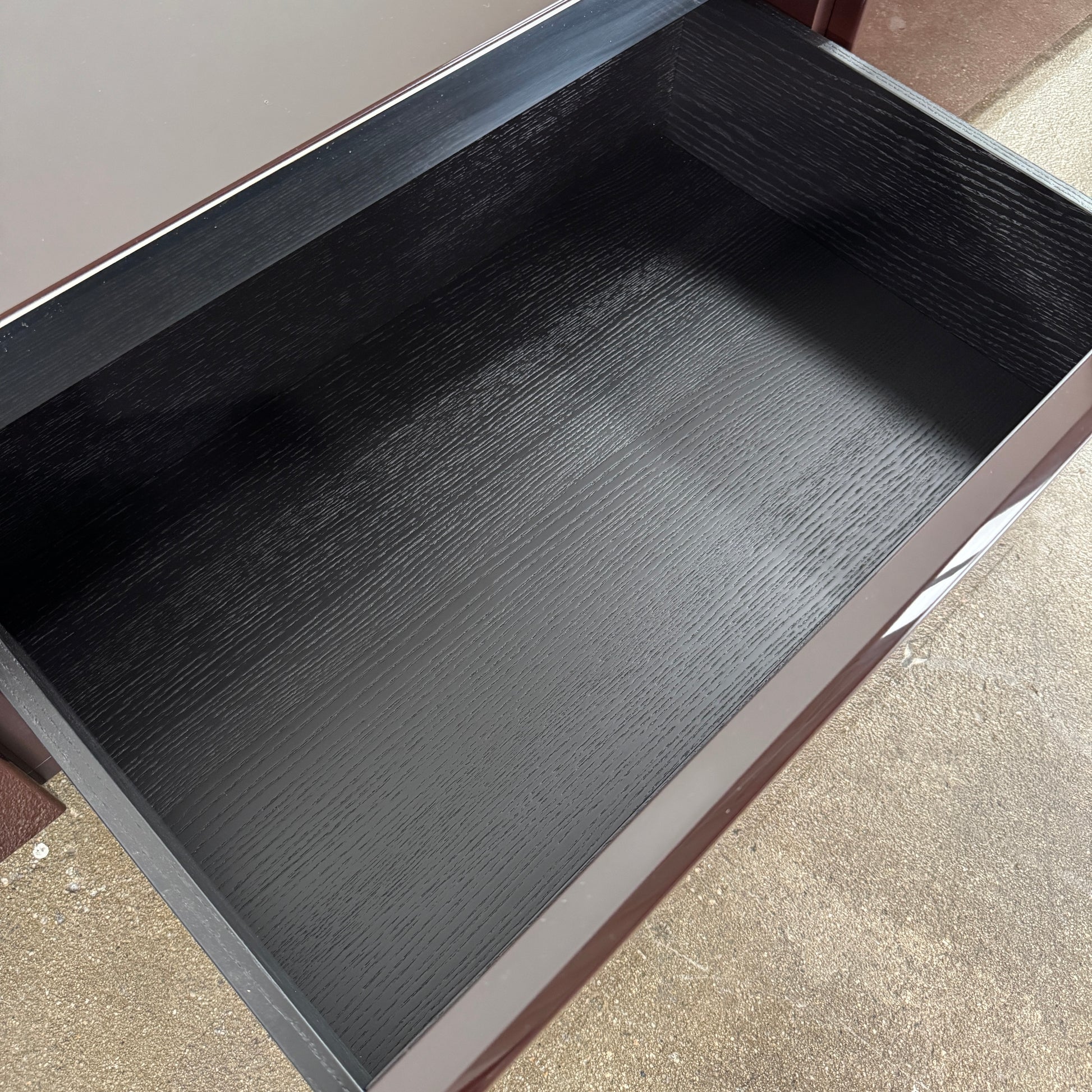 The Minotti Jason Sideboard by Minotti is a long, low-profile, dark brown modern piece with four doors, shown against a white wall on a polished concrete floor.