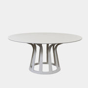 The Cassina Lebeau Outdoor Dining Table by Cassina features a round white porcelain stoneware top and a geometric openwork base, ideal for outdoor dining. Shown on a plain white background.