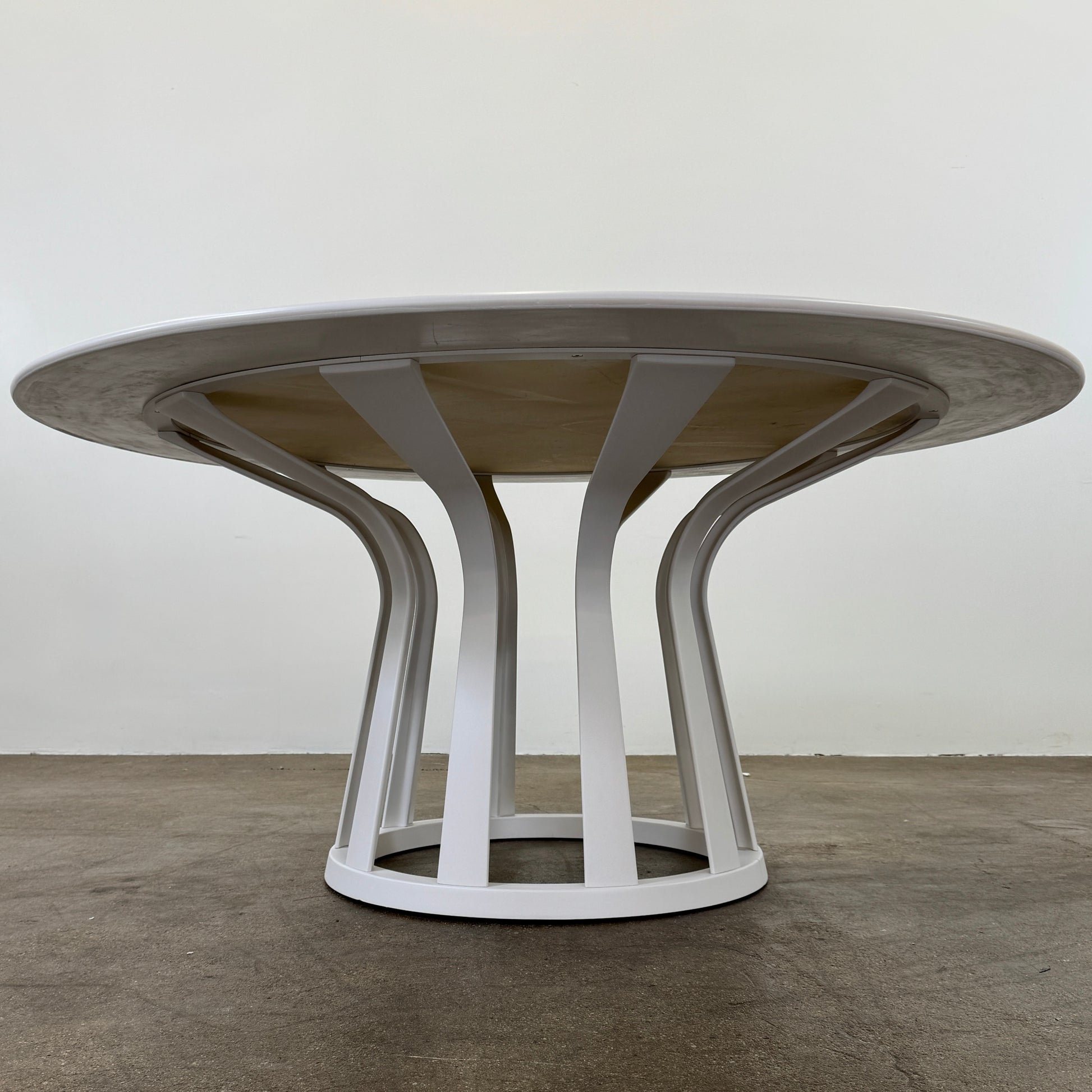The Cassina Lebeau Outdoor Dining Table by Cassina features a round white porcelain stoneware top and a geometric openwork base, ideal for outdoor dining. Shown on a plain white background.