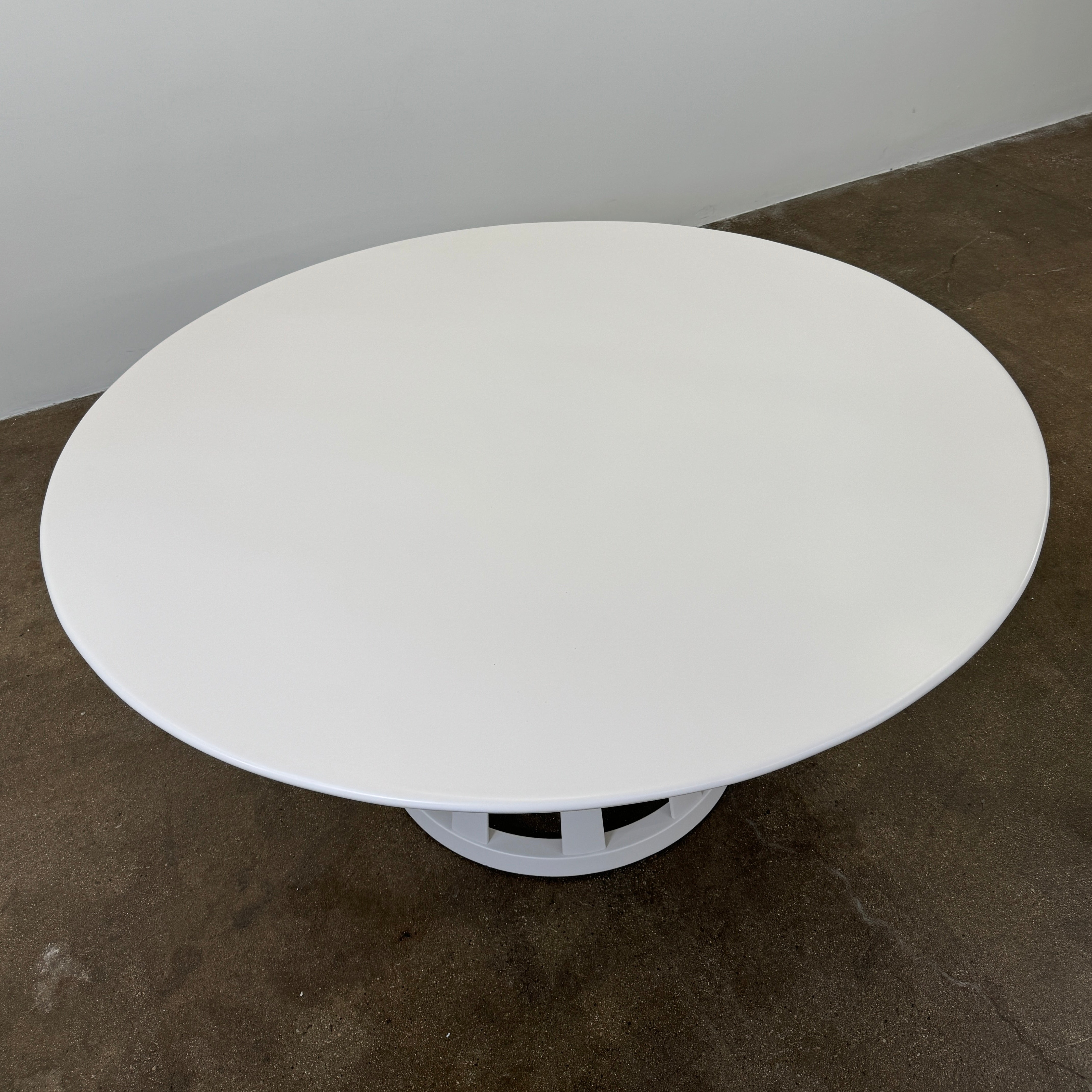 The Cassina Lebeau Outdoor Dining Table by Cassina features a round white porcelain stoneware top and a geometric openwork base, ideal for outdoor dining. Shown on a plain white background.