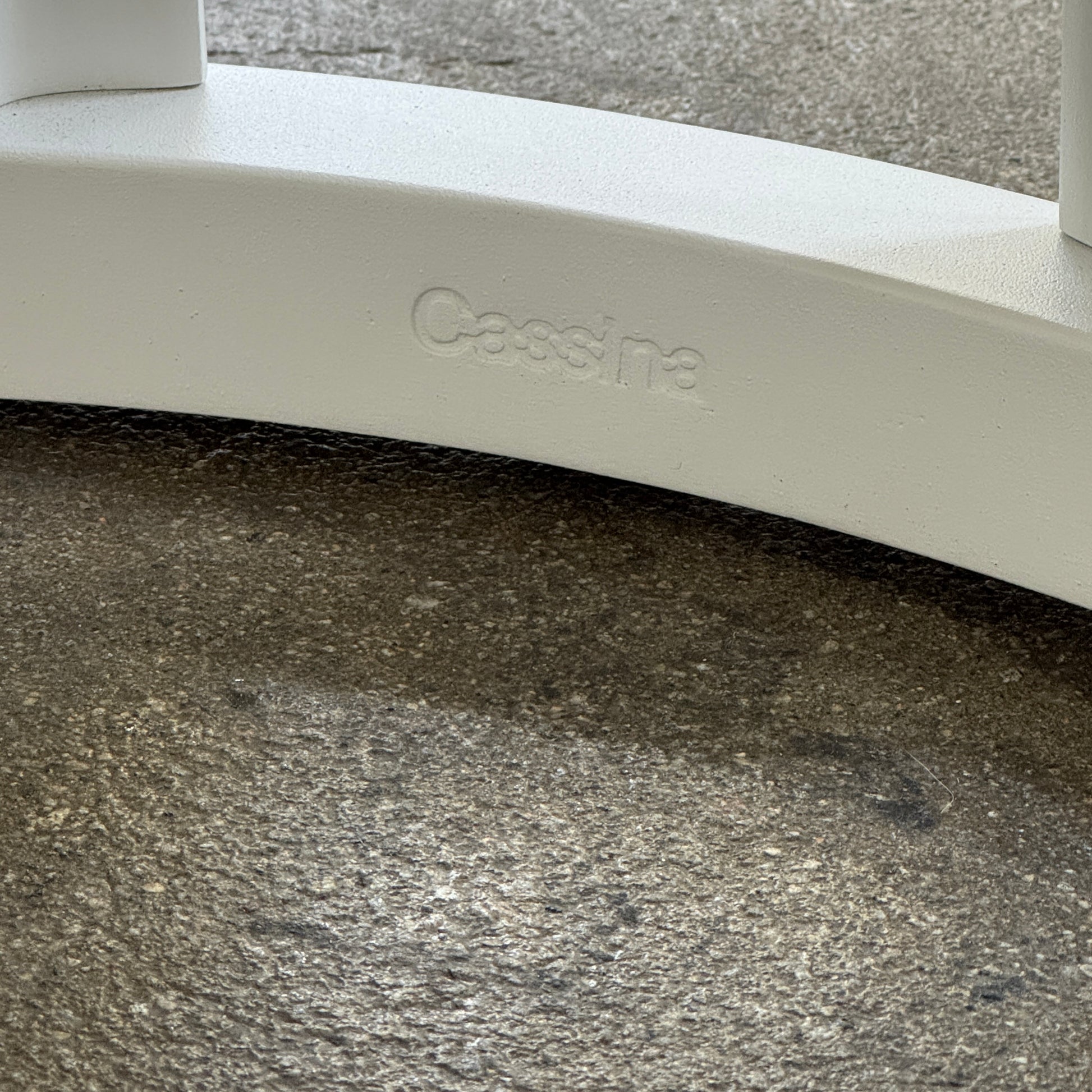 The Cassina Lebeau Outdoor Dining Table by Cassina features a round white porcelain stoneware top and a geometric openwork base, ideal for outdoor dining. Shown on a plain white background.