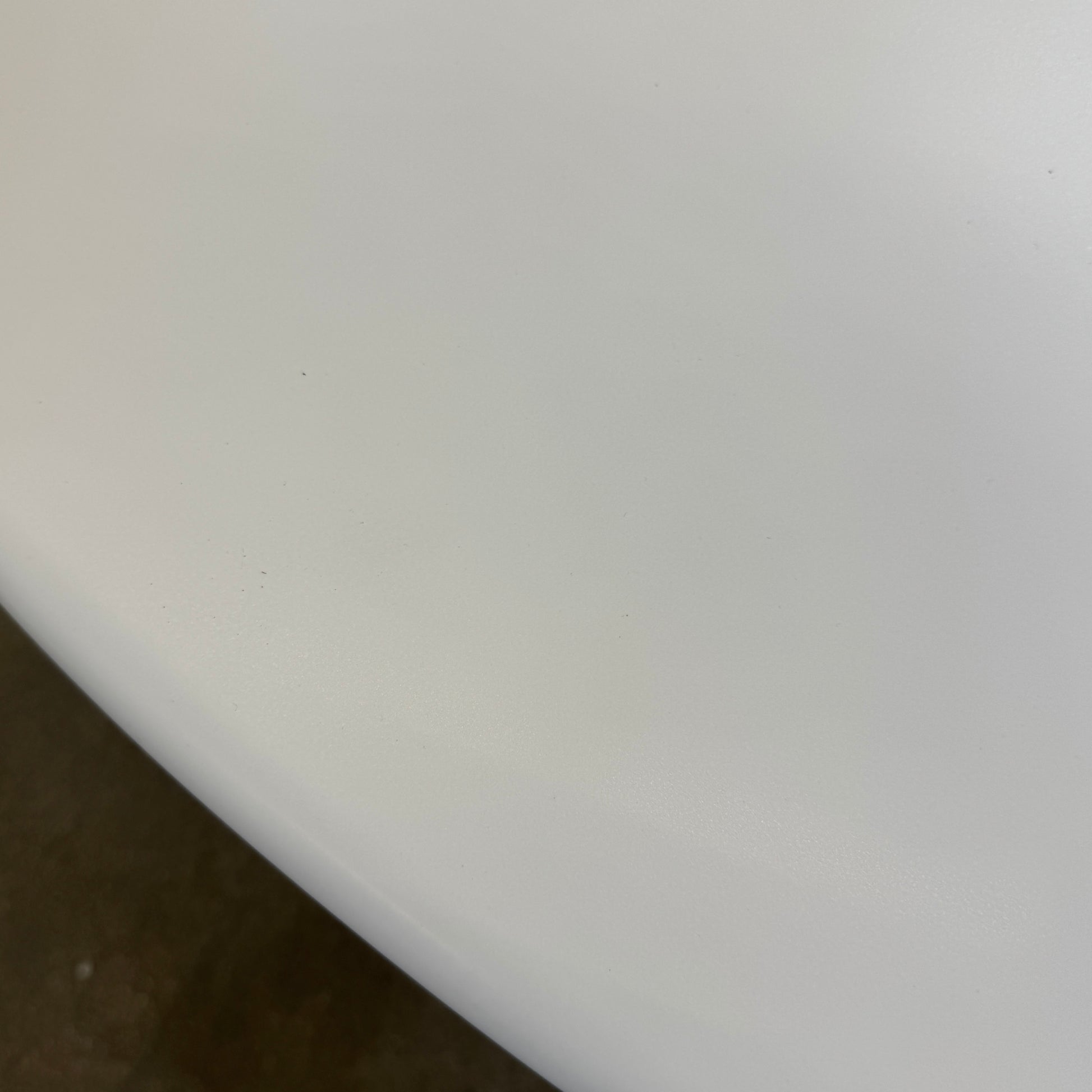 The Cassina Lebeau Outdoor Dining Table by Cassina features a round white porcelain stoneware top and a geometric openwork base, ideal for outdoor dining. Shown on a plain white background.