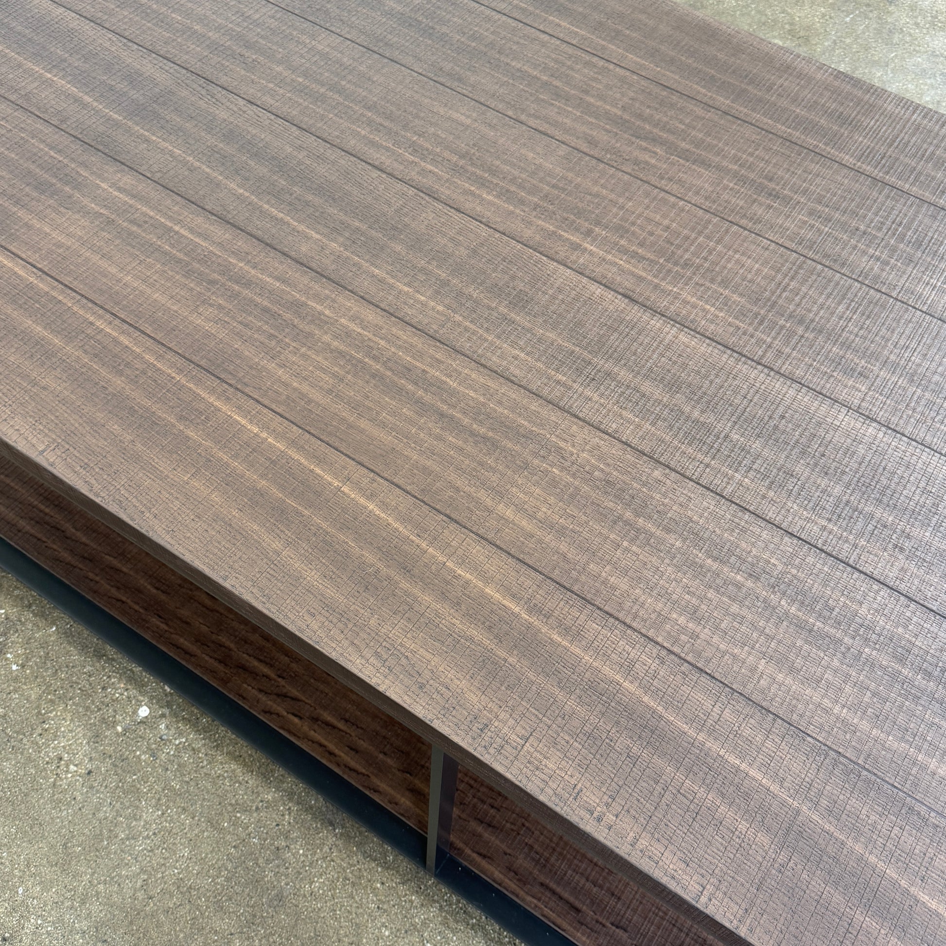 The Maxalto Lithos Coffee Table by Maxalto features a rectangular dark wood top and lower shelf, supported by a minimalist black metal frame, and is displayed against a plain white background.