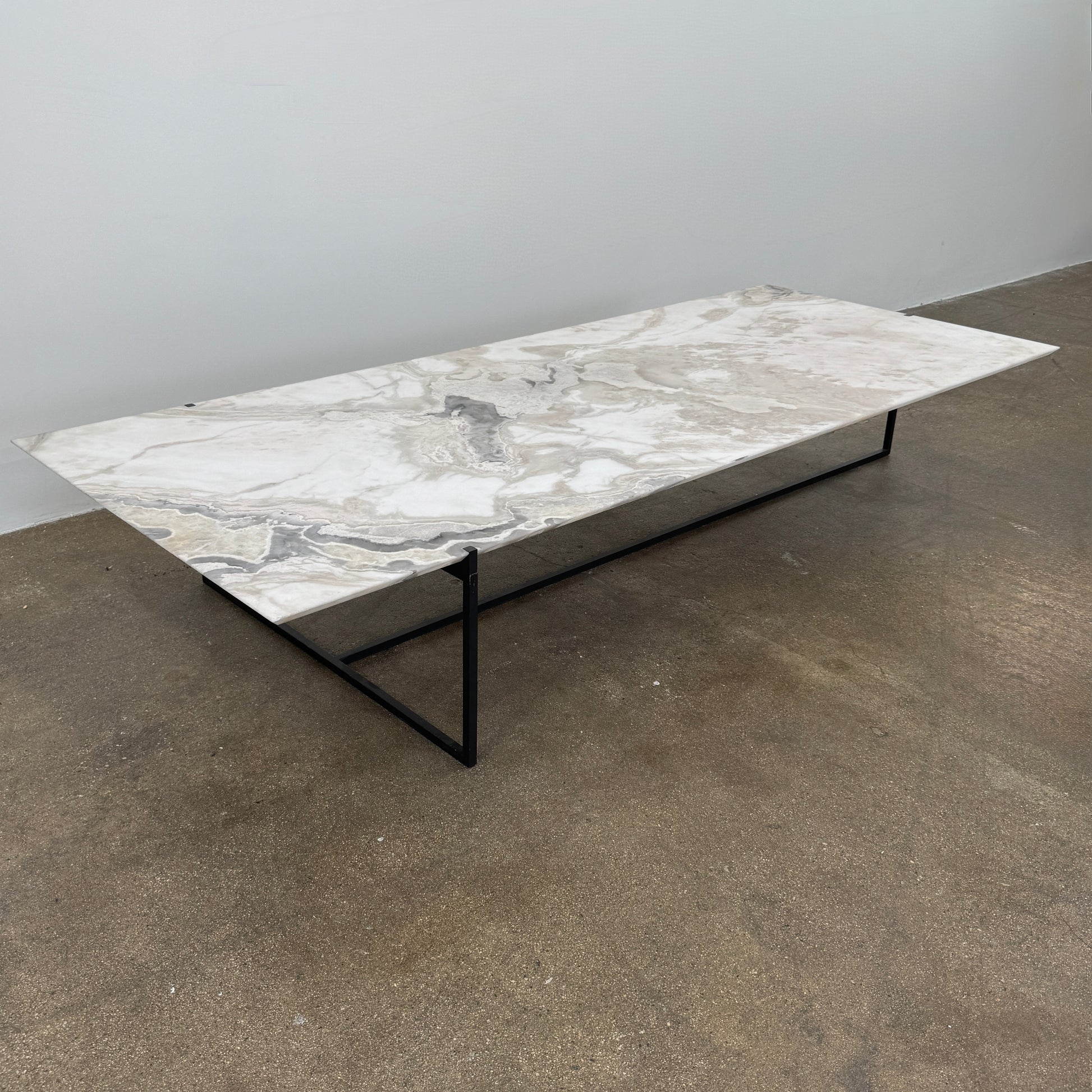 The Baxter Icaro Rectangular Coffee Table by Baxter features a Polar White Marble top with off-white, gray, and beige veining on a slim black metal frame, shown against a white background for a modern look.