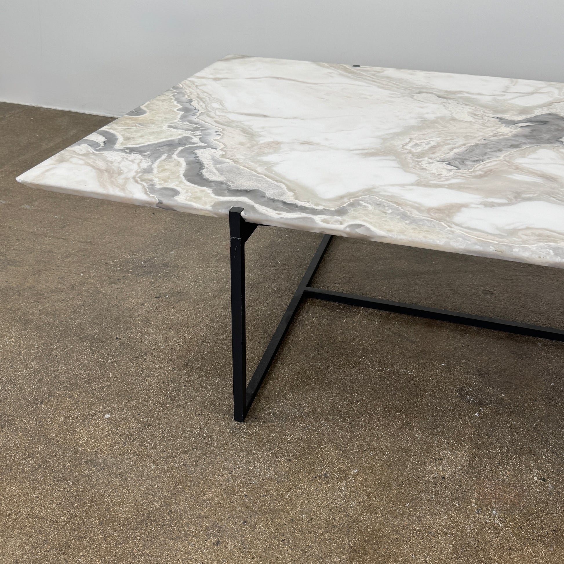 The Baxter Icaro Rectangular Coffee Table by Baxter features a Polar White Marble top with off-white, gray, and beige veining on a slim black metal frame, shown against a white background for a modern look.