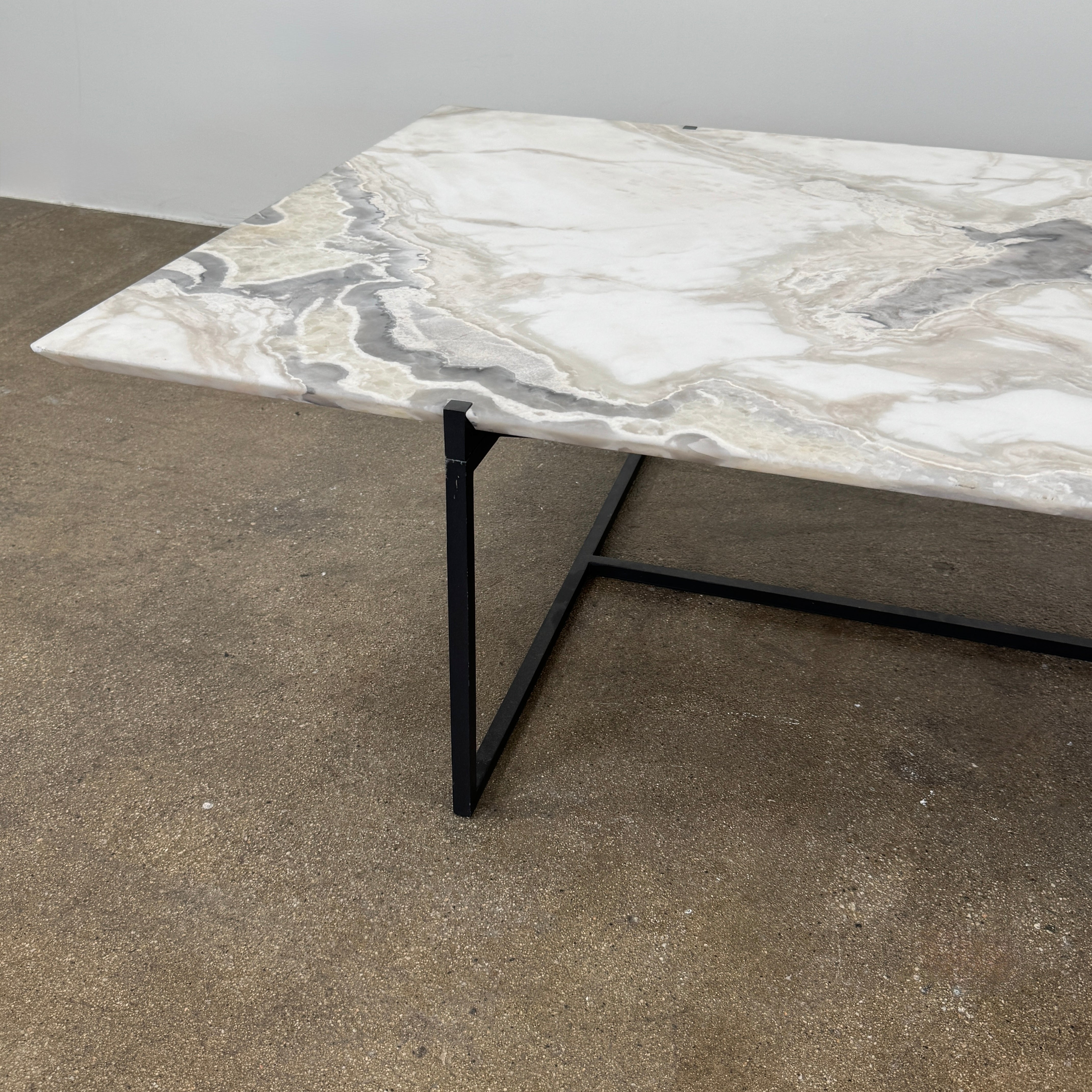 The Baxter Icaro Rectangular Coffee Table by Baxter features a Polar White Marble top with off-white, gray, and beige veining on a slim black metal frame, shown against a white background for a modern look.