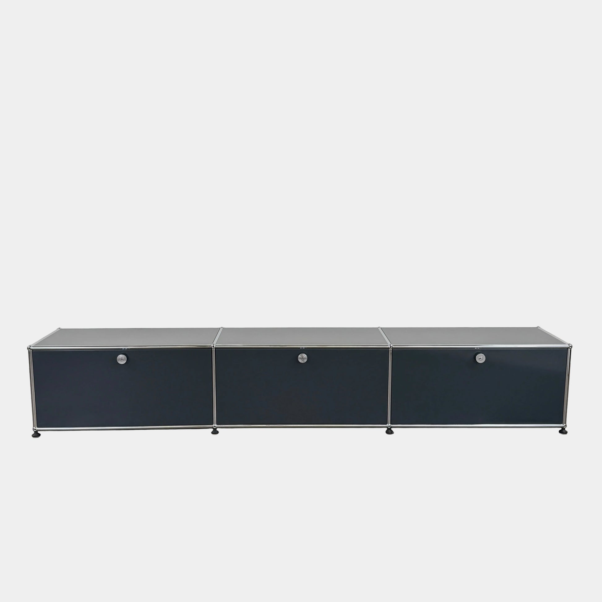 The USM Haller Low Console - Three Flap Door Unit features three black flap doors with round knobs and a silver frame, shown against a plain white background.