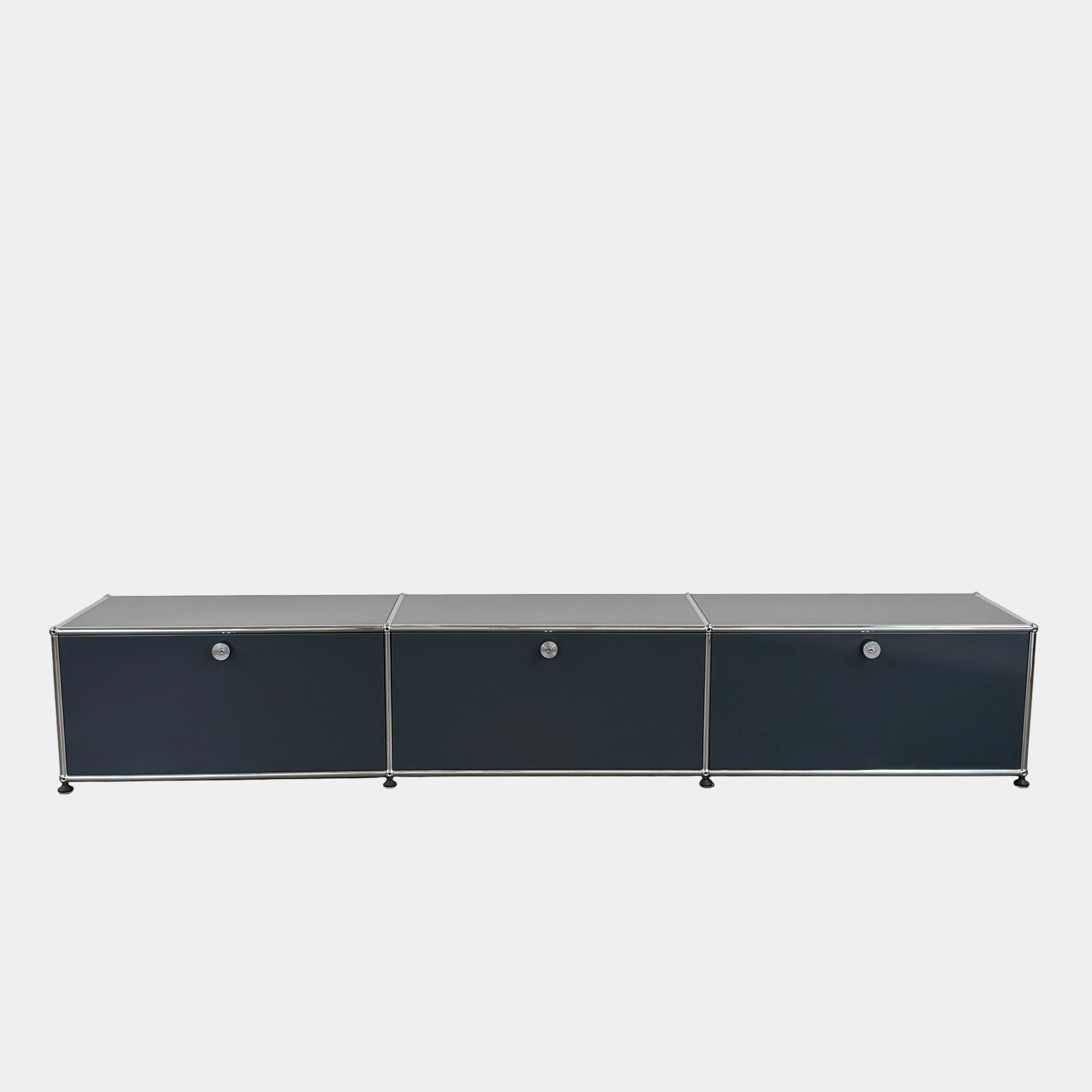 The USM Haller Low Console - Three Flap Door Unit features three black flap doors with round knobs and a silver frame, shown against a plain white background.