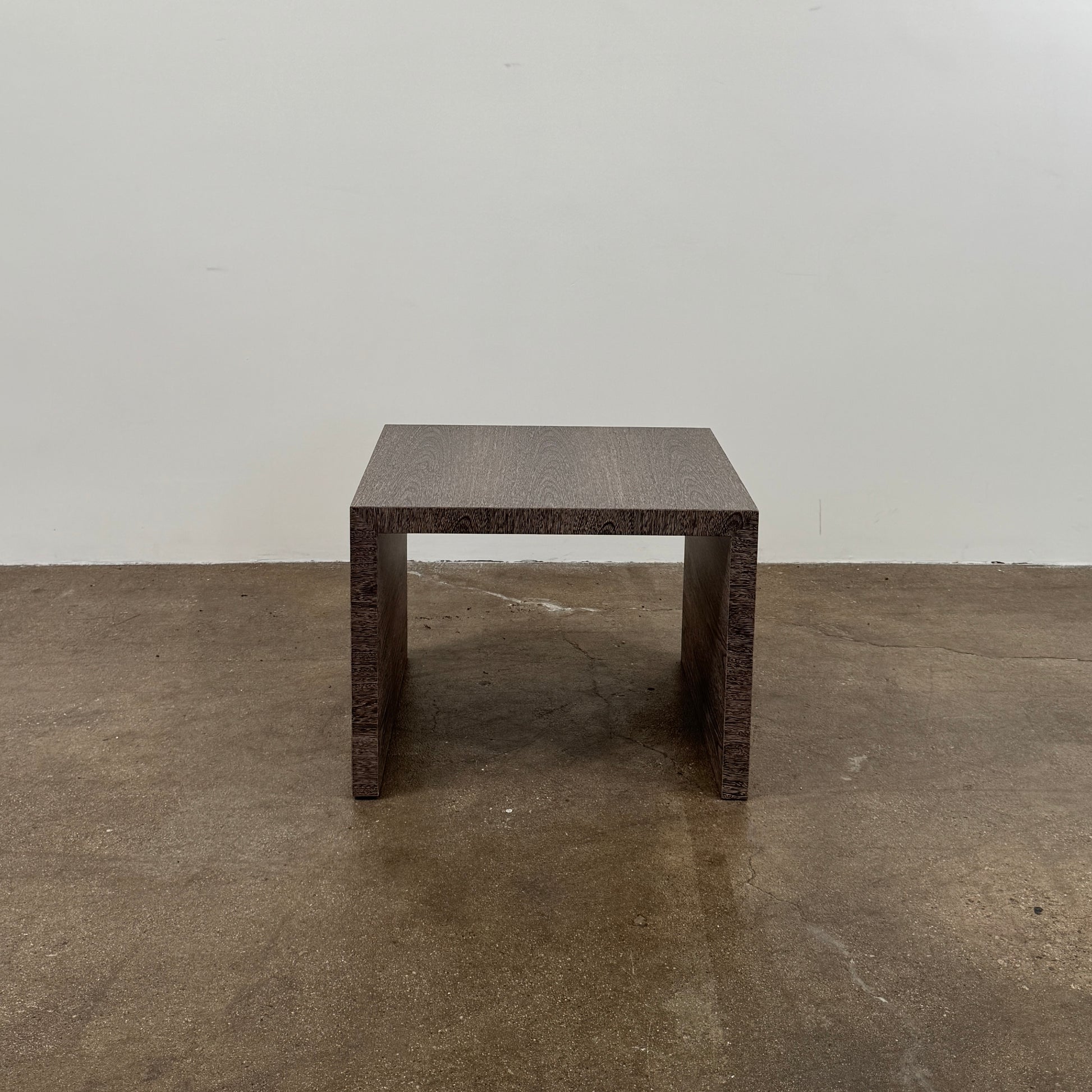 The Maxalto Arke Side Table by Maxalto is a square Sucupira wood accent table with a minimalist design, thick legs, and an open space beneath, shown against a plain white background.