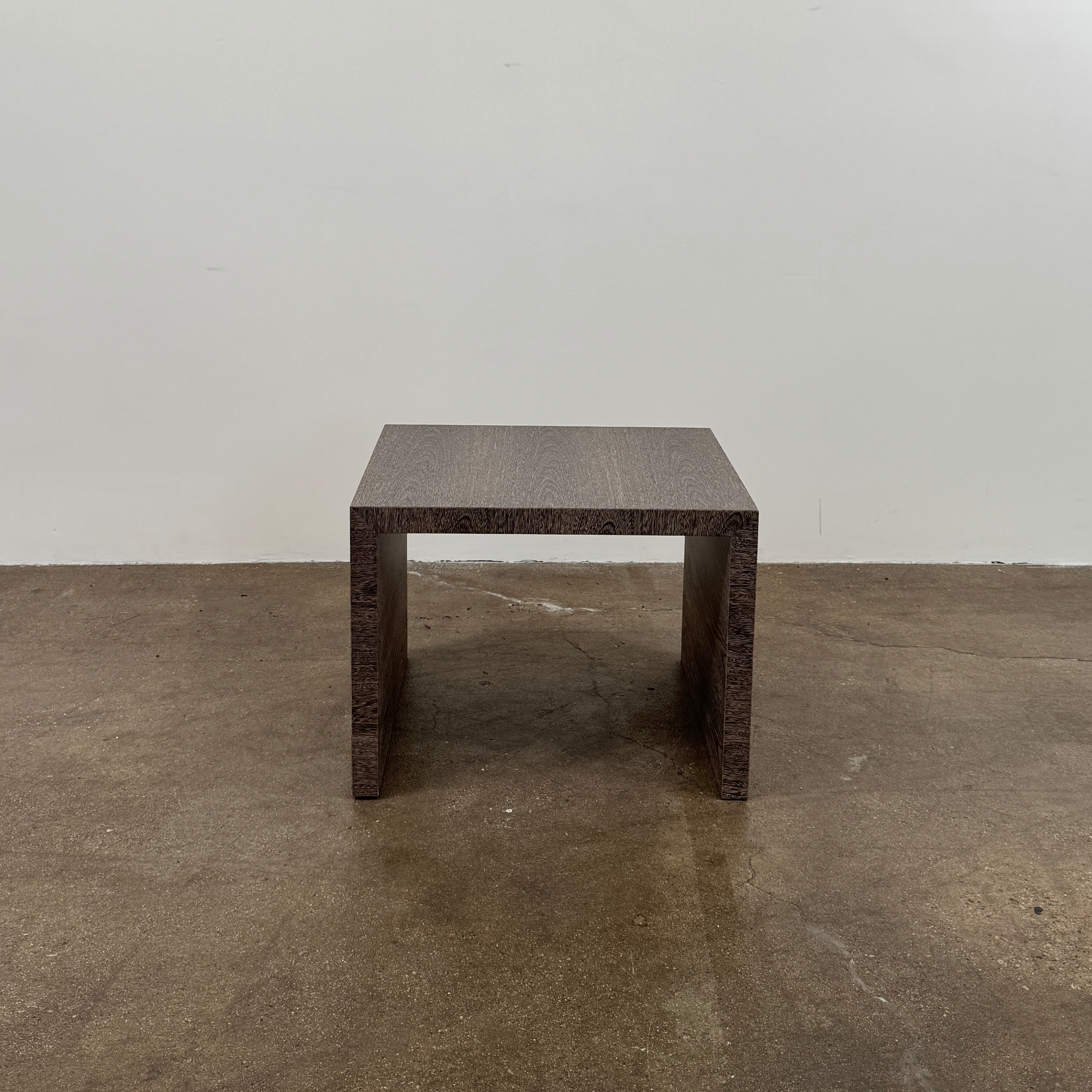 The Maxalto Arke Side Table by Maxalto is a square Sucupira wood accent table with a minimalist design, thick legs, and an open space beneath, shown against a plain white background.
