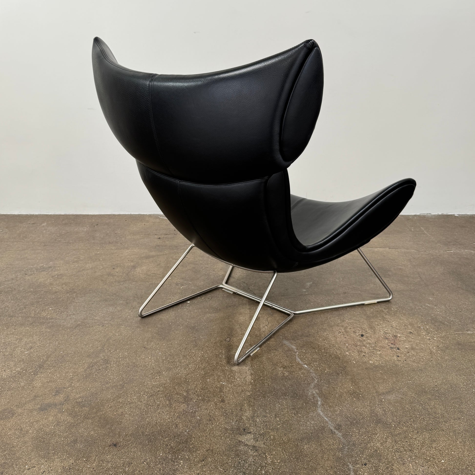 The BoConcept Imola Armchair by BoConcept is a modern black designer lounge chair with a curved leather seat and backrest, supported by slim metal legs, shown against a plain white background—an iconic piece inspired by the original Imola design.