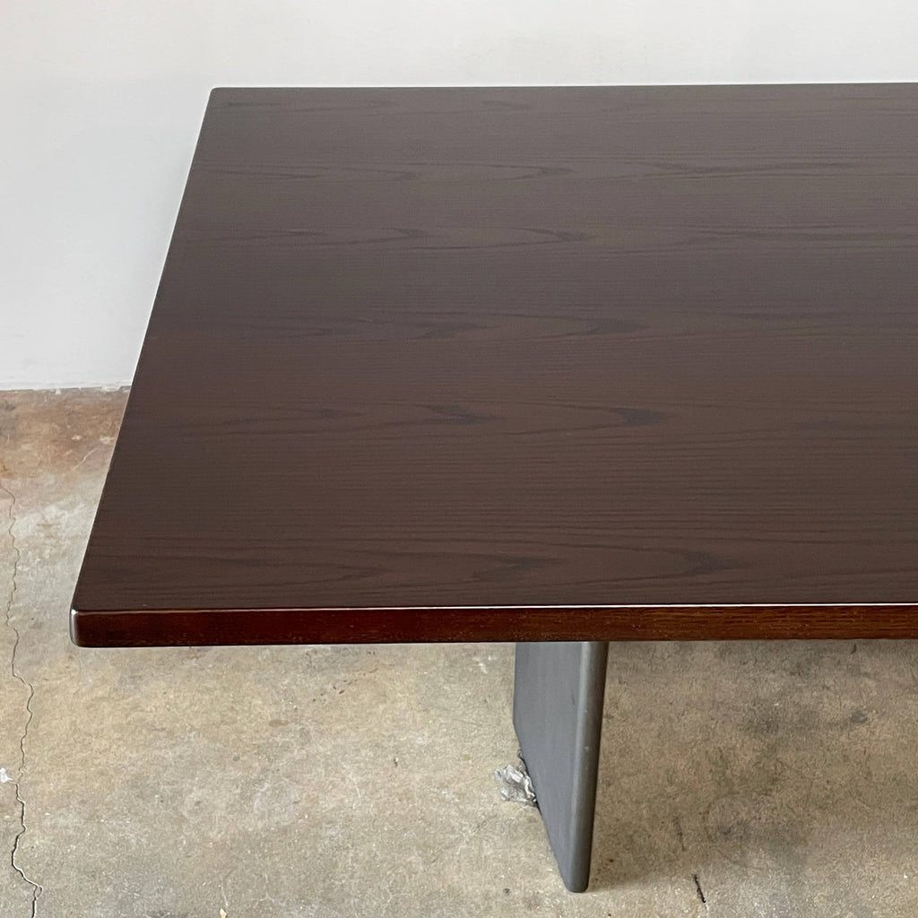 A Minotti Morgan dining table, dark brown with a smooth surface and angled legs, isolated on a white background.