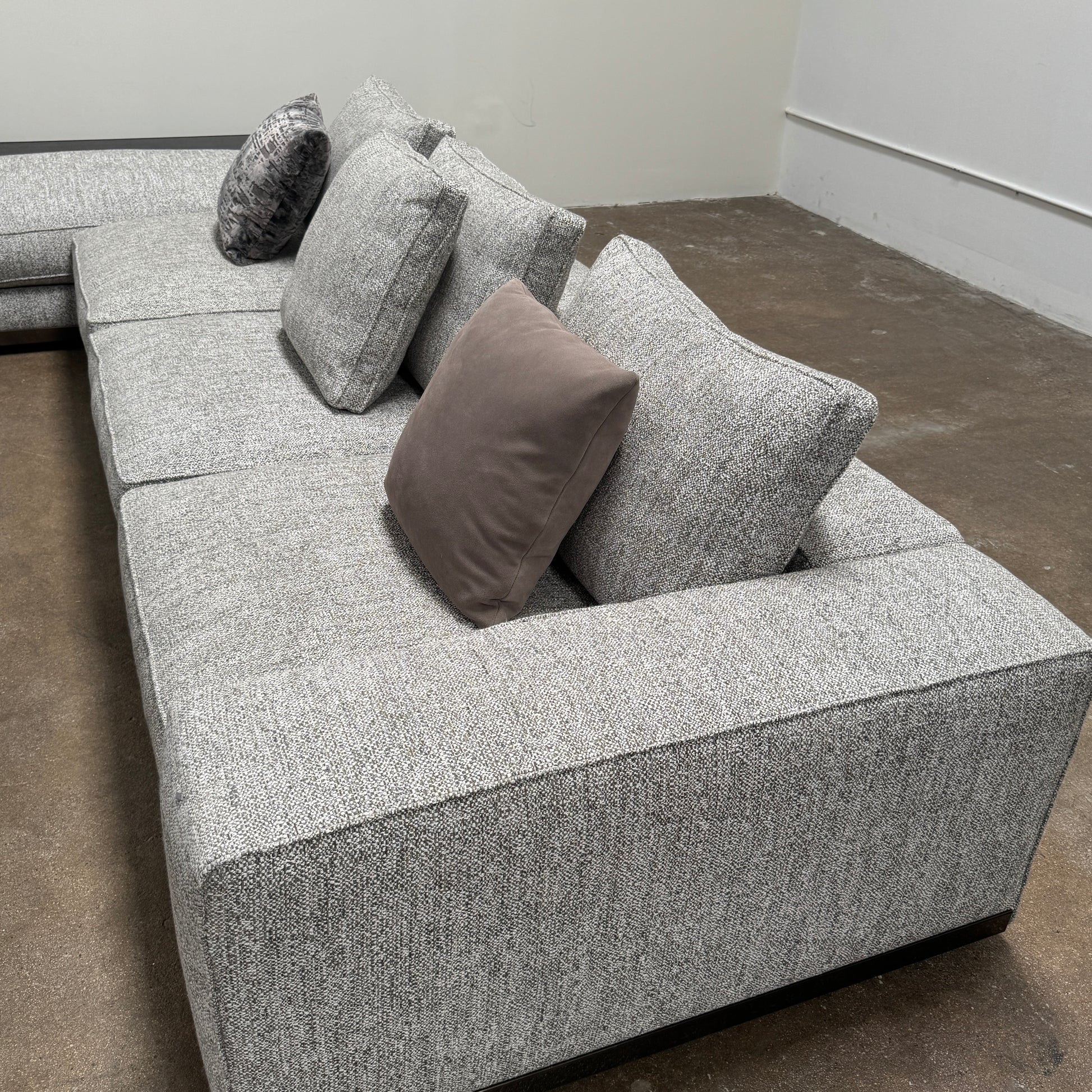 The Minotti West Sectional Sofa with Side Table and Clive Bench by Minotti features a large, L-shaped modern design with gray upholstery, multiple plush cushions, and an integrated side table—perfect for elevating luxury living rooms—all set against a plain white background.